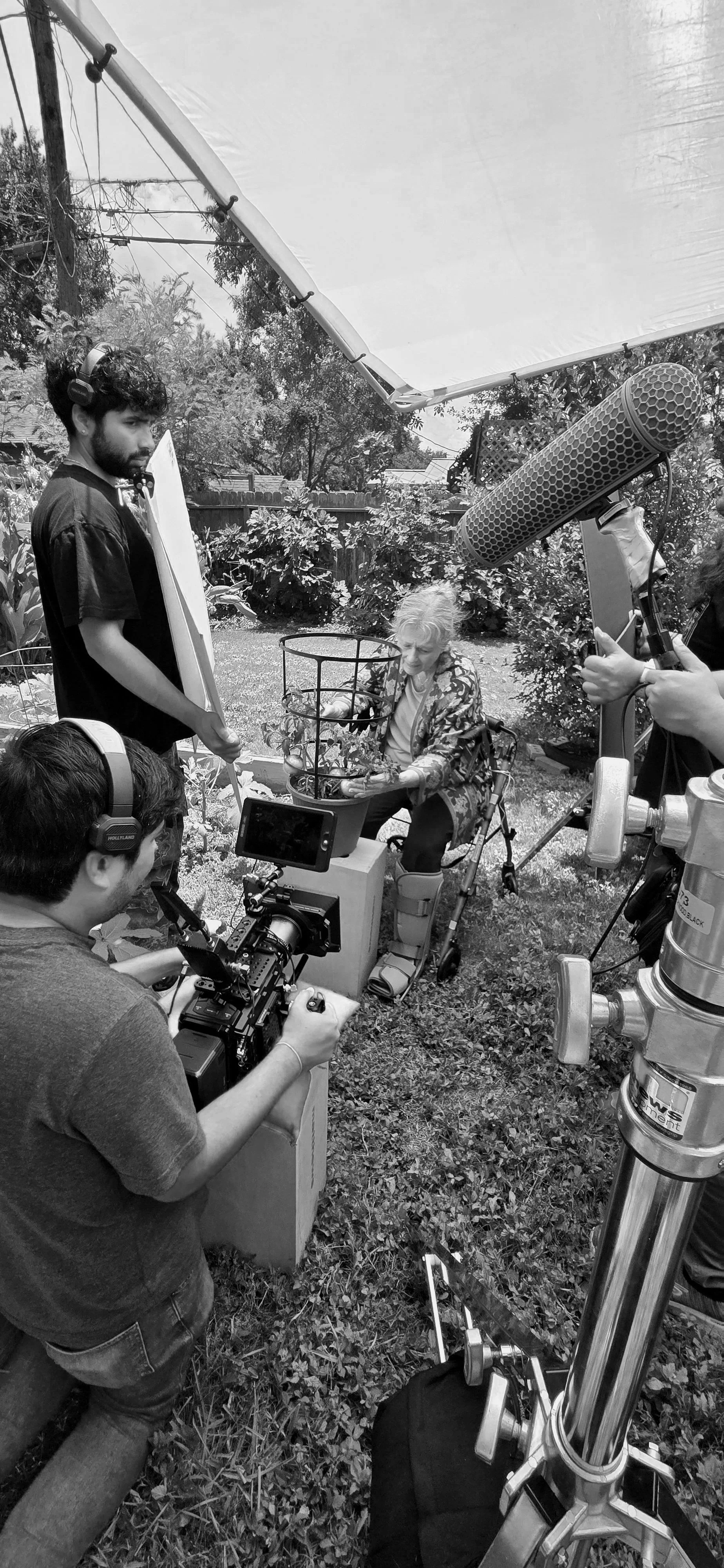Coastal Bend Corpus Christi Filming crew working outdoors with filming equipment, an older woman planting a flower in a garden, and a camera operator filming her.