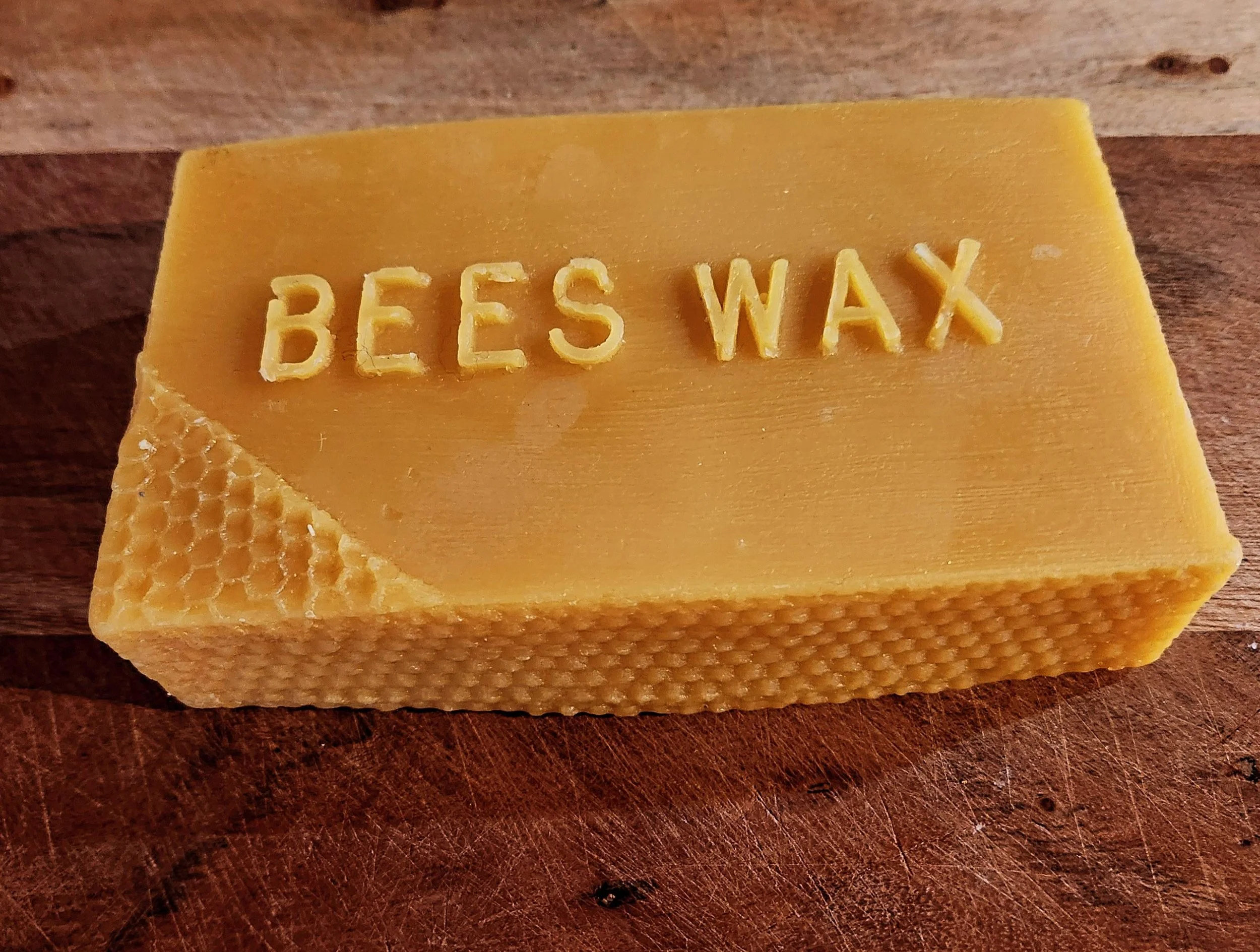 A block of yellow cheese with the words 'BEE'S WAX' carved into the top surface.