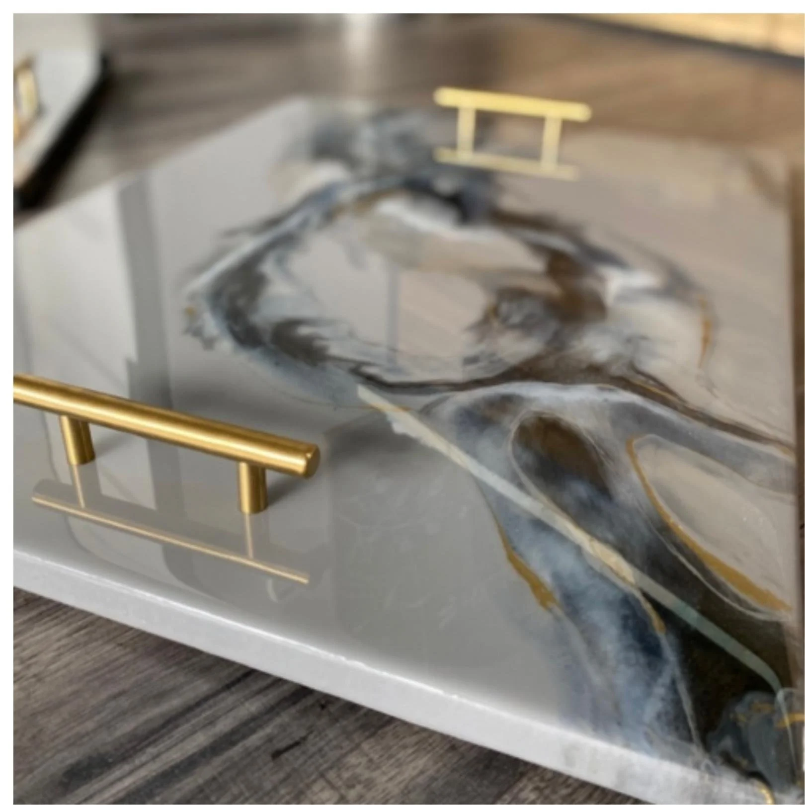 Decorative display of a marble-like material with black, white, gray, and gold swirls, accented by a gold rail in front.