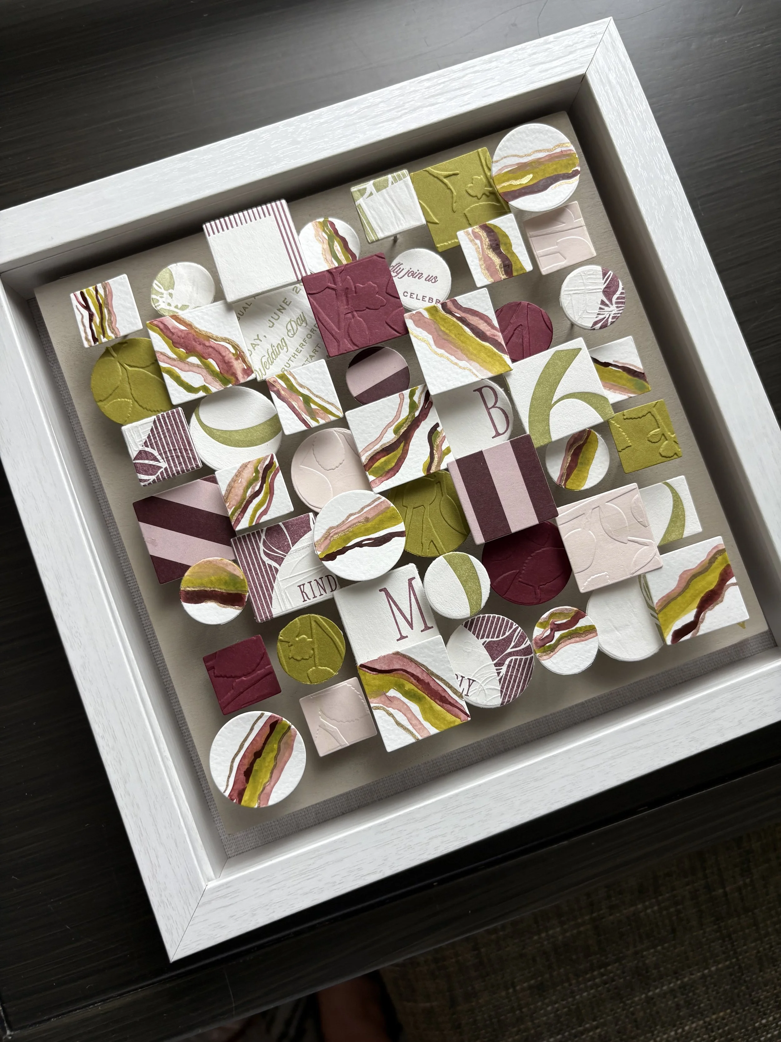 A white box containing various decorated ceramic or paper tiles in shades of white, pink, red, and green with marbled and embossed patterns.