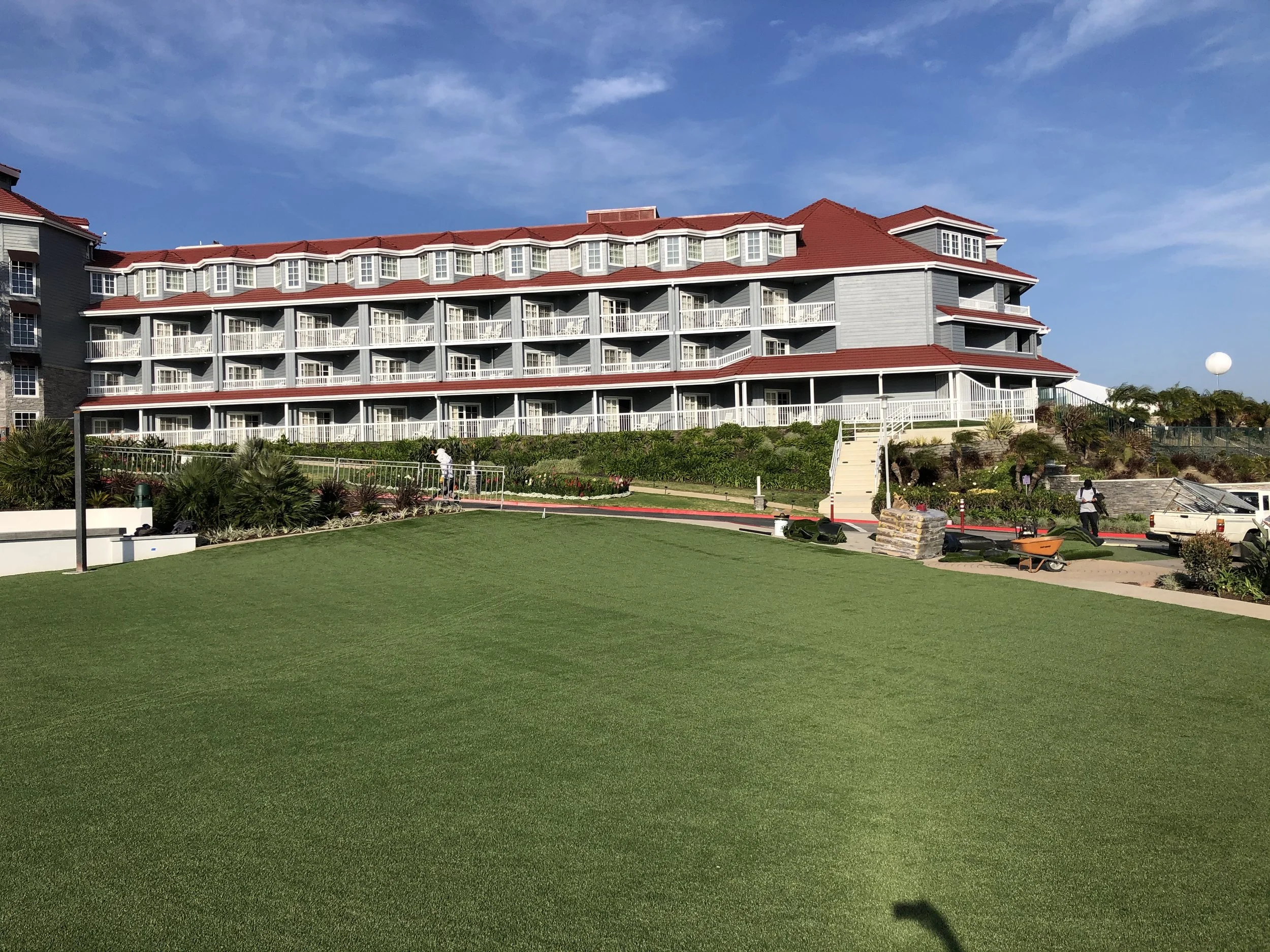 Green artificial turf lawn in front of hotel with building supplies and worker