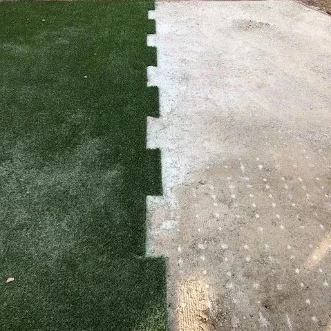 Half of a sports field with artificial turf on the left and concrete on the right, separated by a jagged white line.