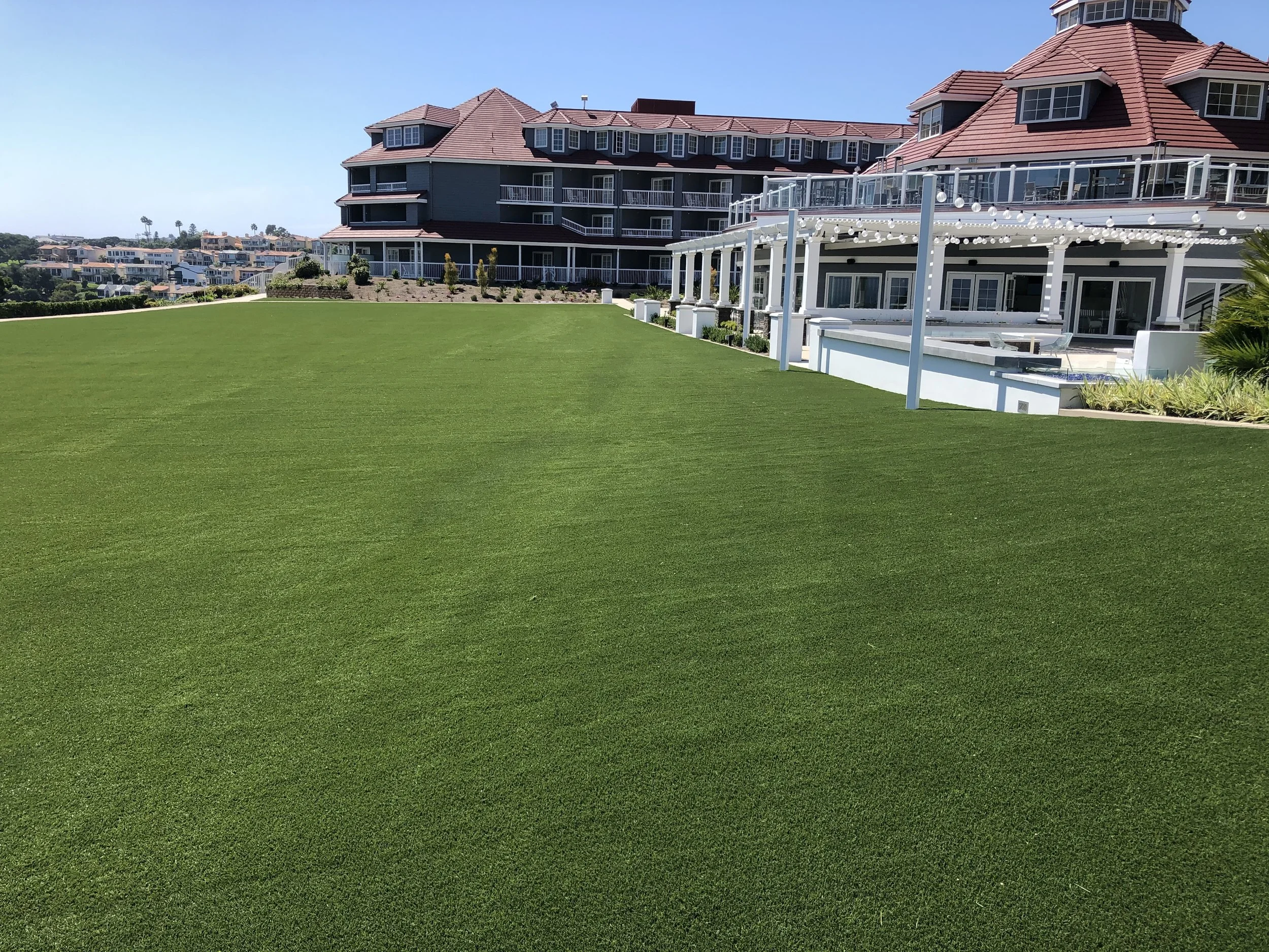 Green artificial turf front lawn of a hotel, in front of buildings and a pagoda