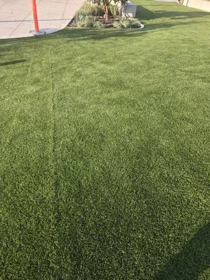 Green artificial turf with obvious seam needing to be repaired