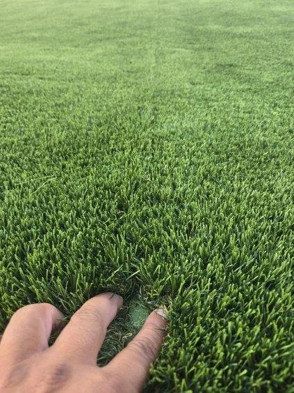 Green artificial turf exposing a failed seam