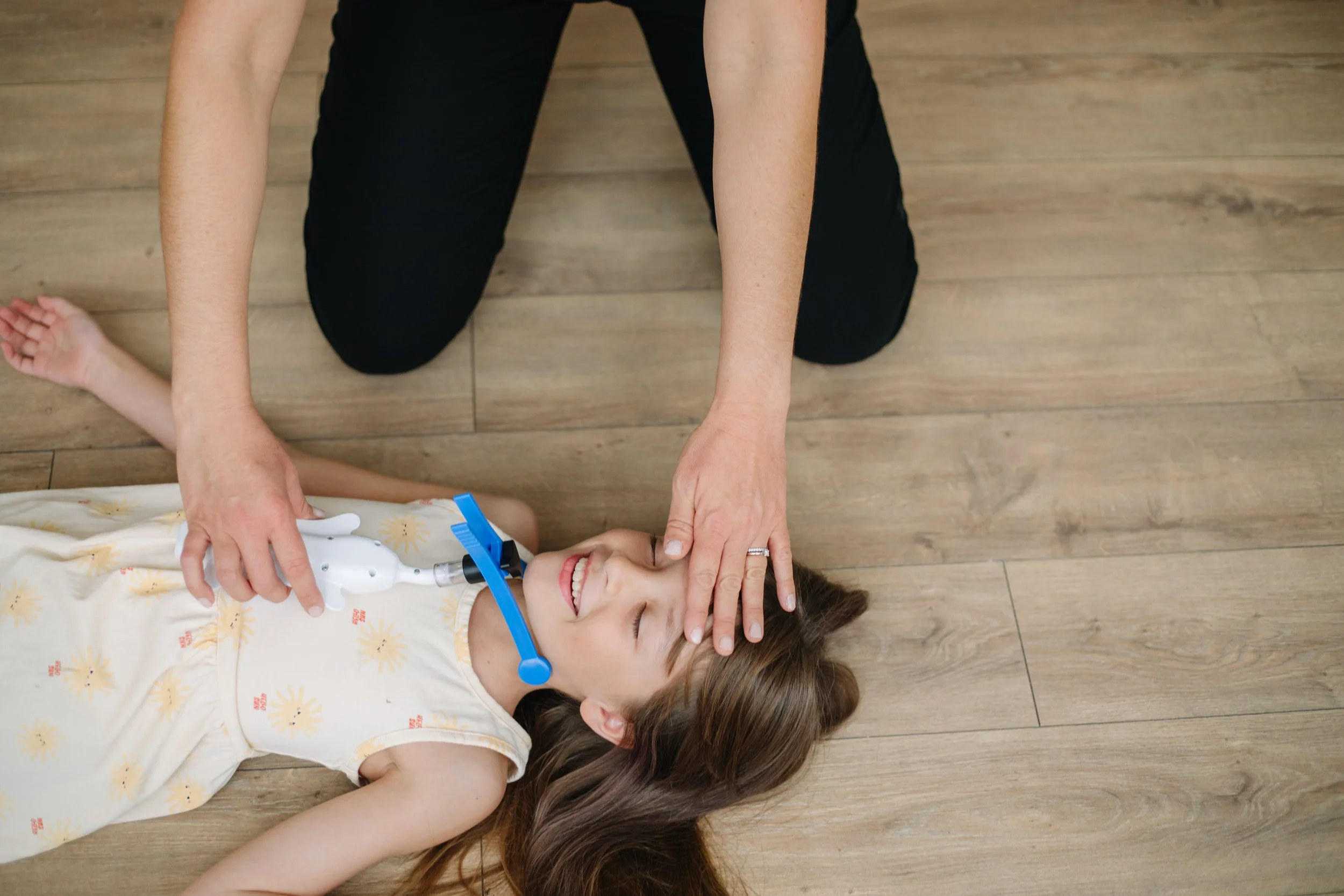 A child lying on the floor during an occupational therapy session in Dallas, TX, participating in NeuroAdaptive Therapy