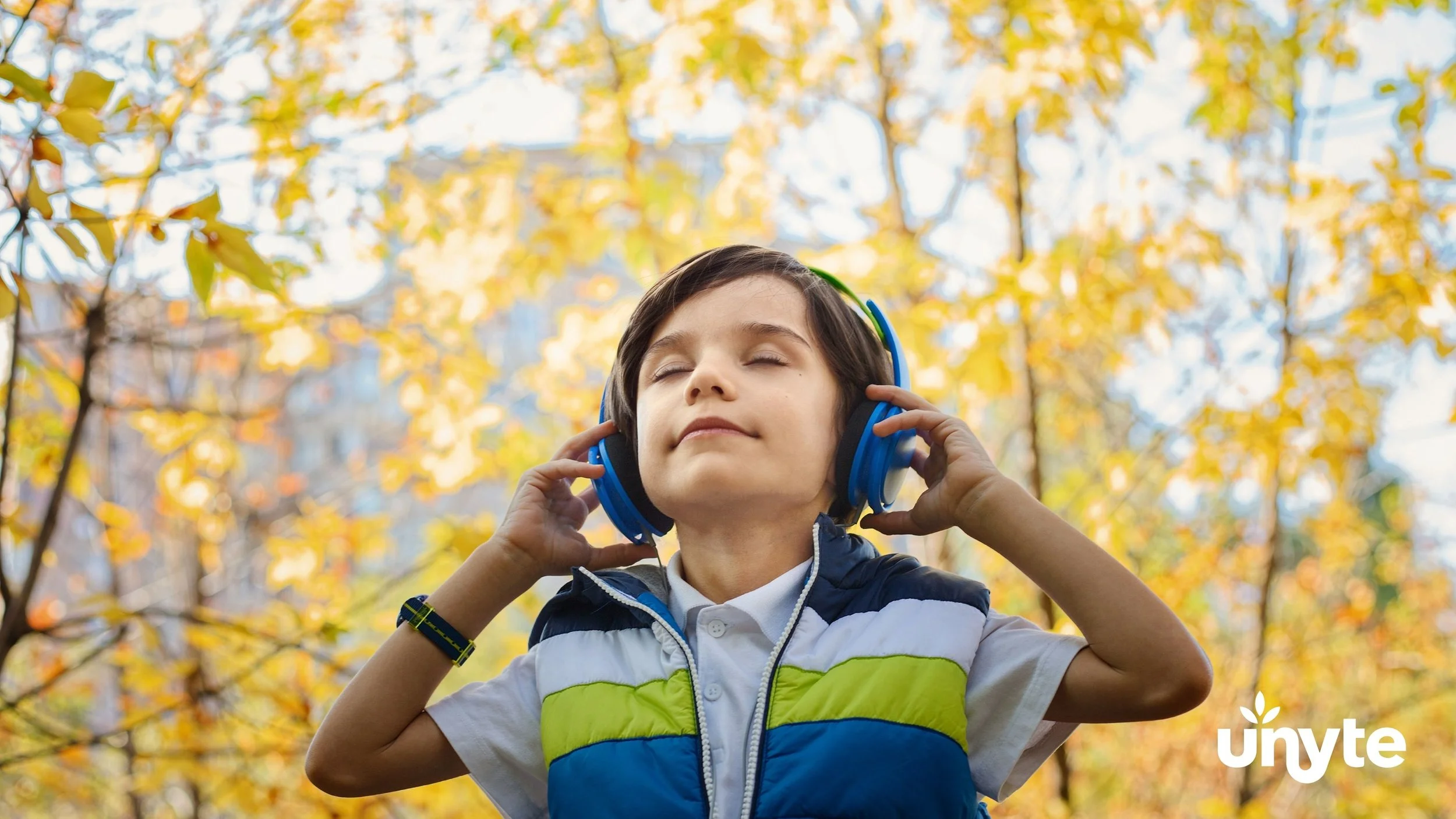 A young boy outdoors, wearing headphones, participating in The Safe and Sound Protocol (SSP) in Dallas, TX - an evidence-based listening therapy designed to help regulate the nervous system.