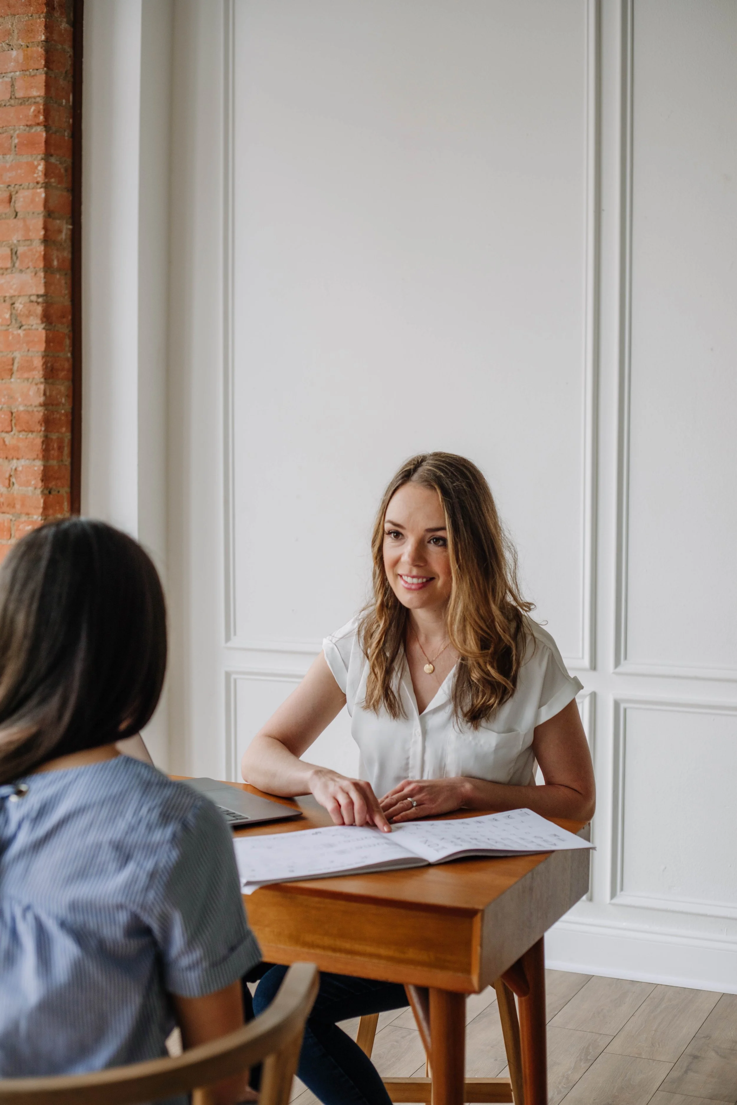 A parent of an autistic child sitting at a desk across from an occupational therapist in Dallas, TX, participating in training on diet, lifestyle, and supplementation strategies