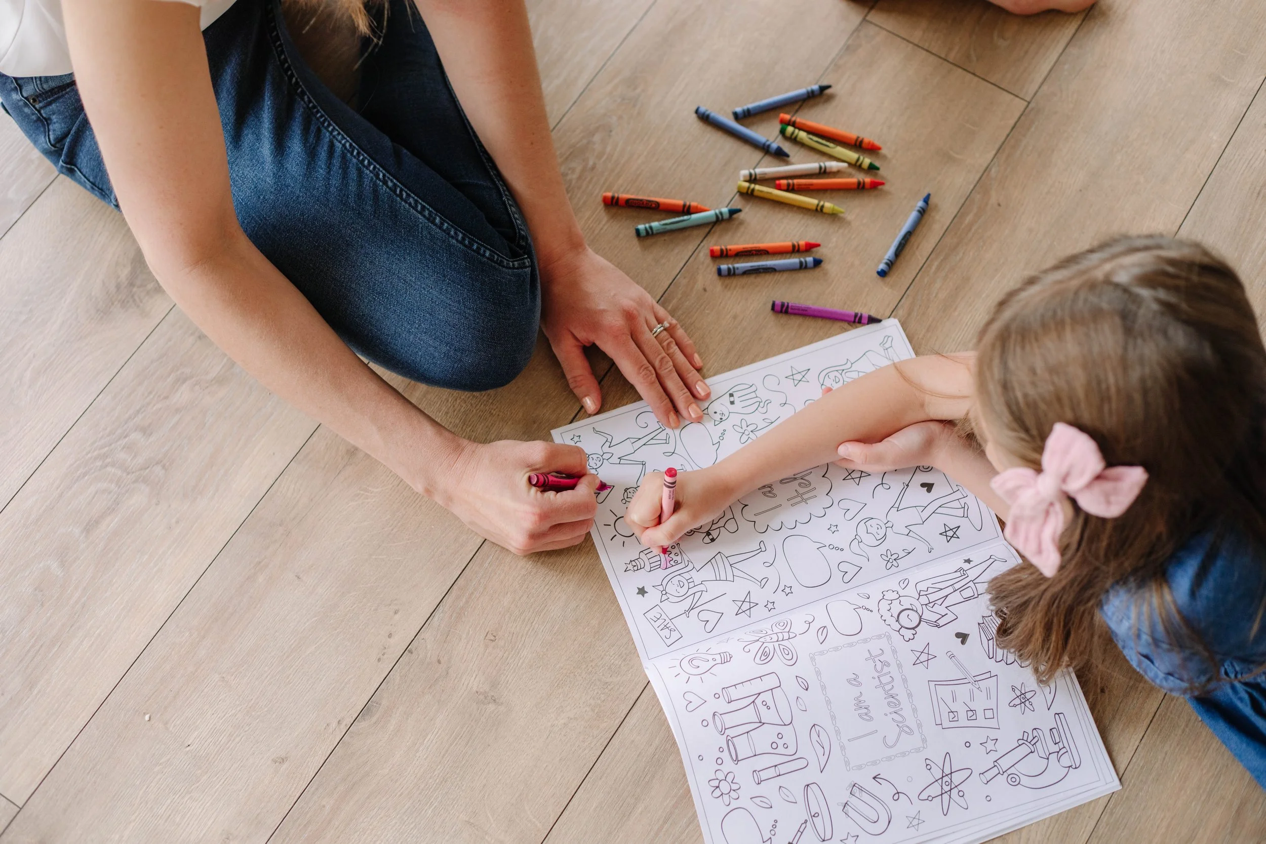 An occupational therapist and a young girl sitting on the floor coloring with crayons, working on grasp and hand strength during OT for kids in Dallas, TX