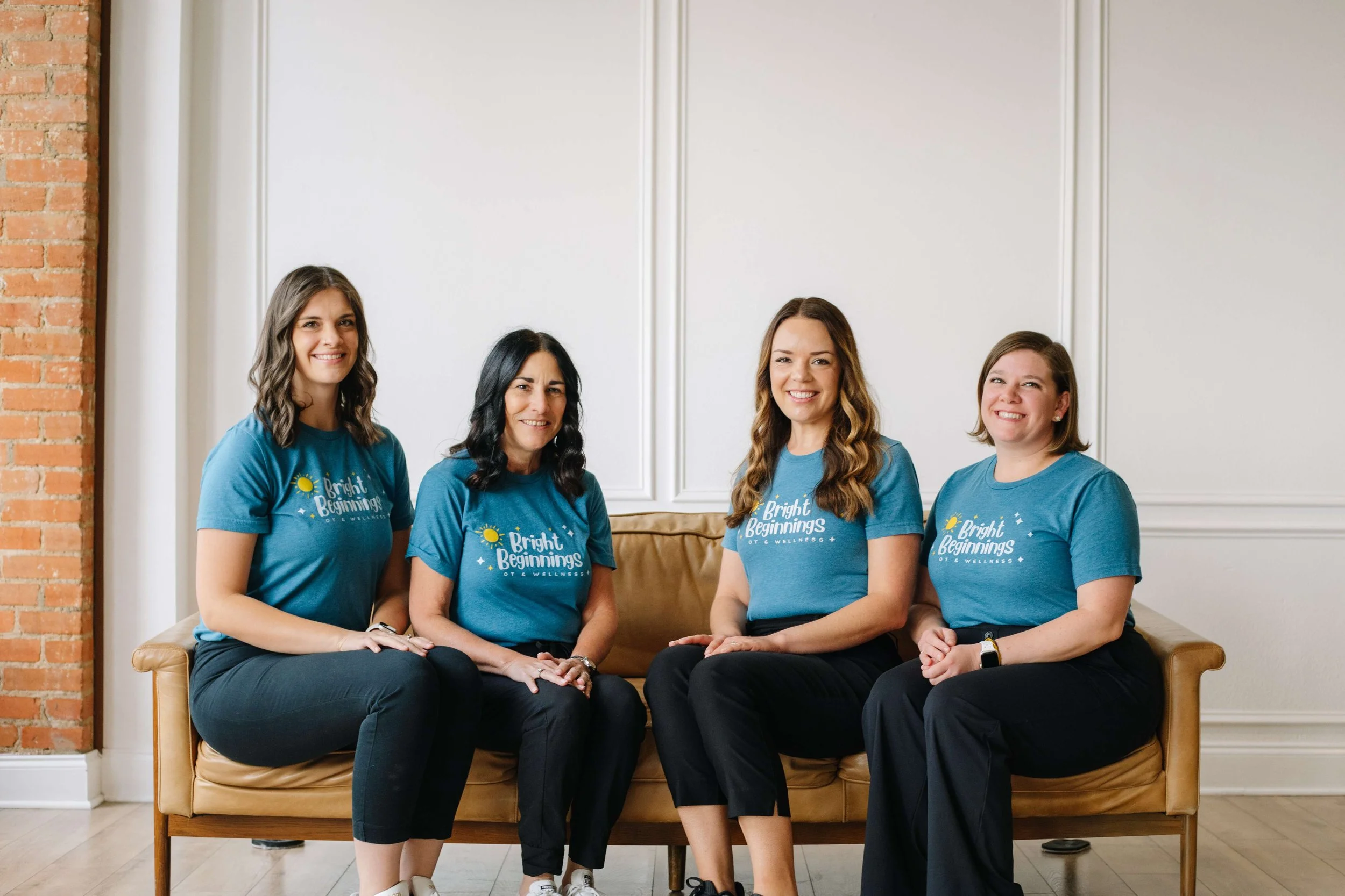 The team of occupational therapists at Bright Beginnings Occupational Therapy and Wellness in Dallas, TX, all sitting on a cough smiling.