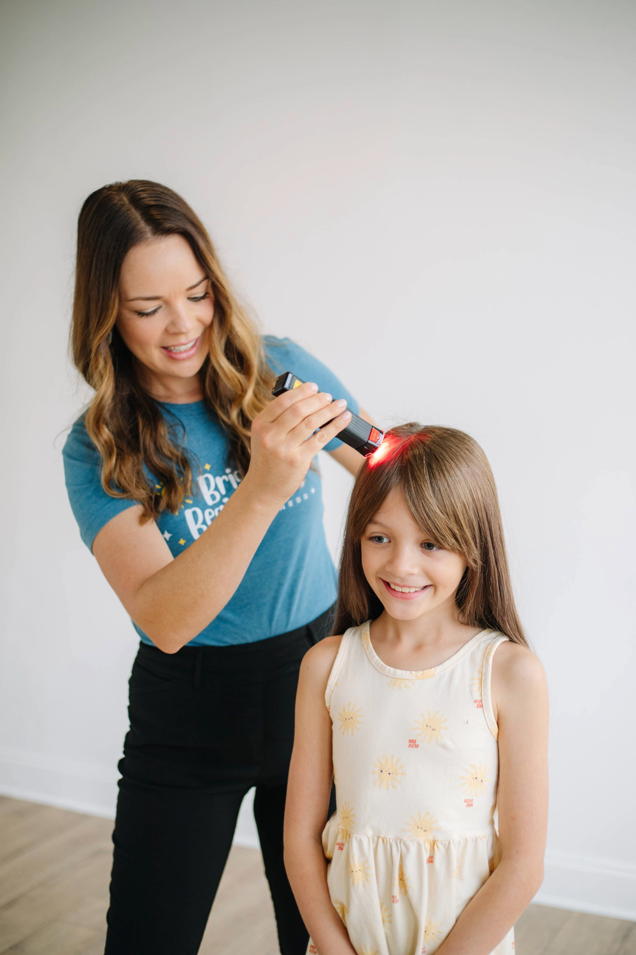 An occupational therapist with long wavy hair is using low-level laser light therapy with a child during occupational therapy for autism in Dallas, TX
