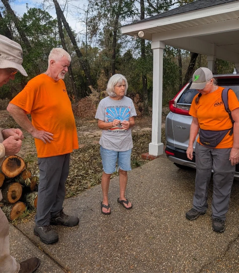 PAR volunteers pray with a homeowner after cleaning up property