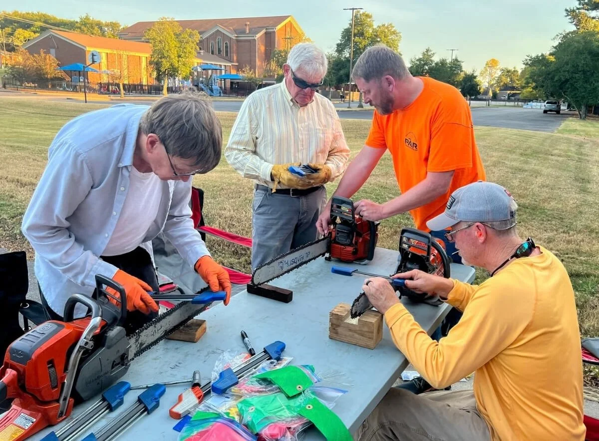 Volunteers servicing chainsaws