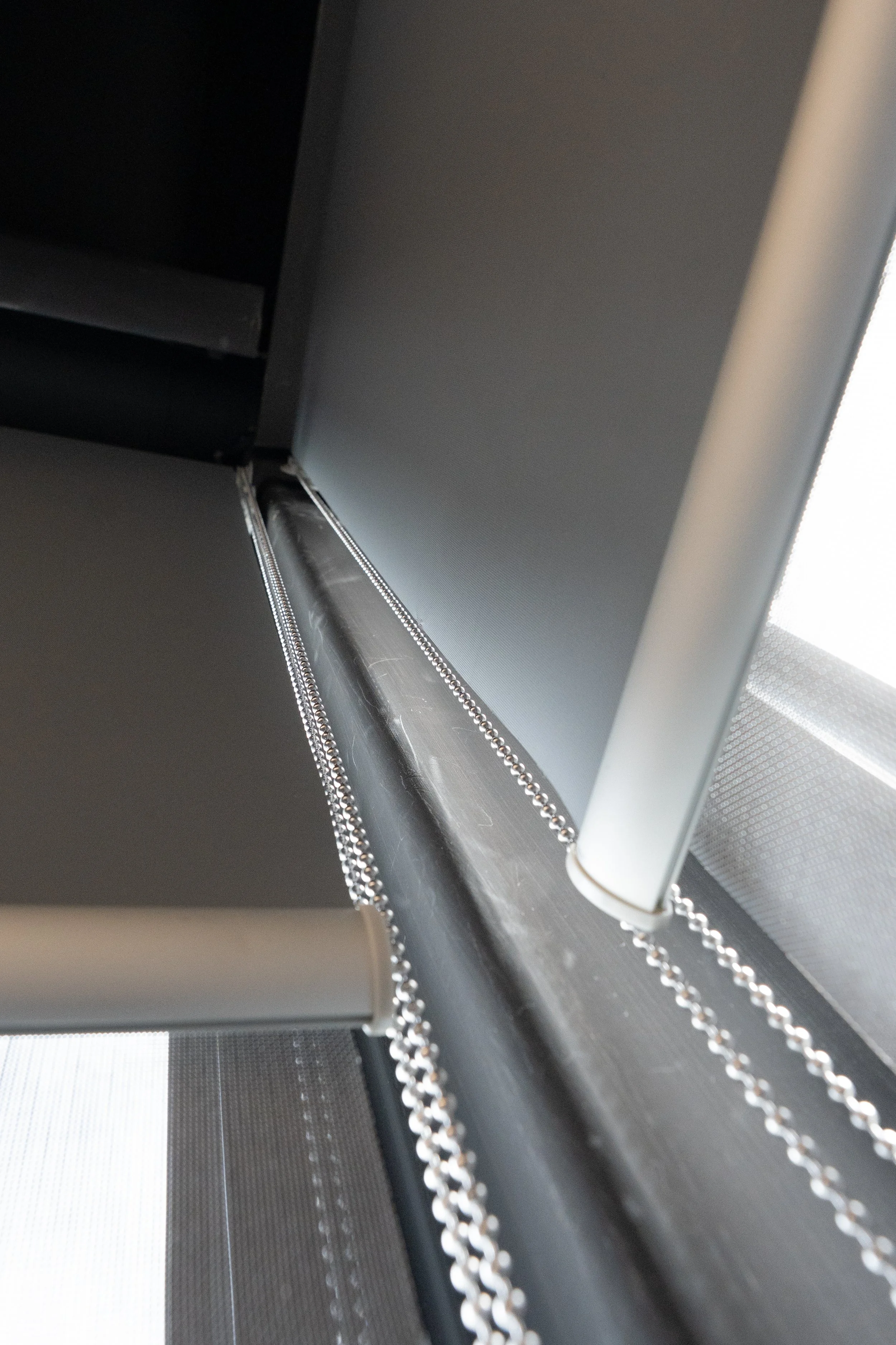Close-up of a double roller blind bracket and chains from below