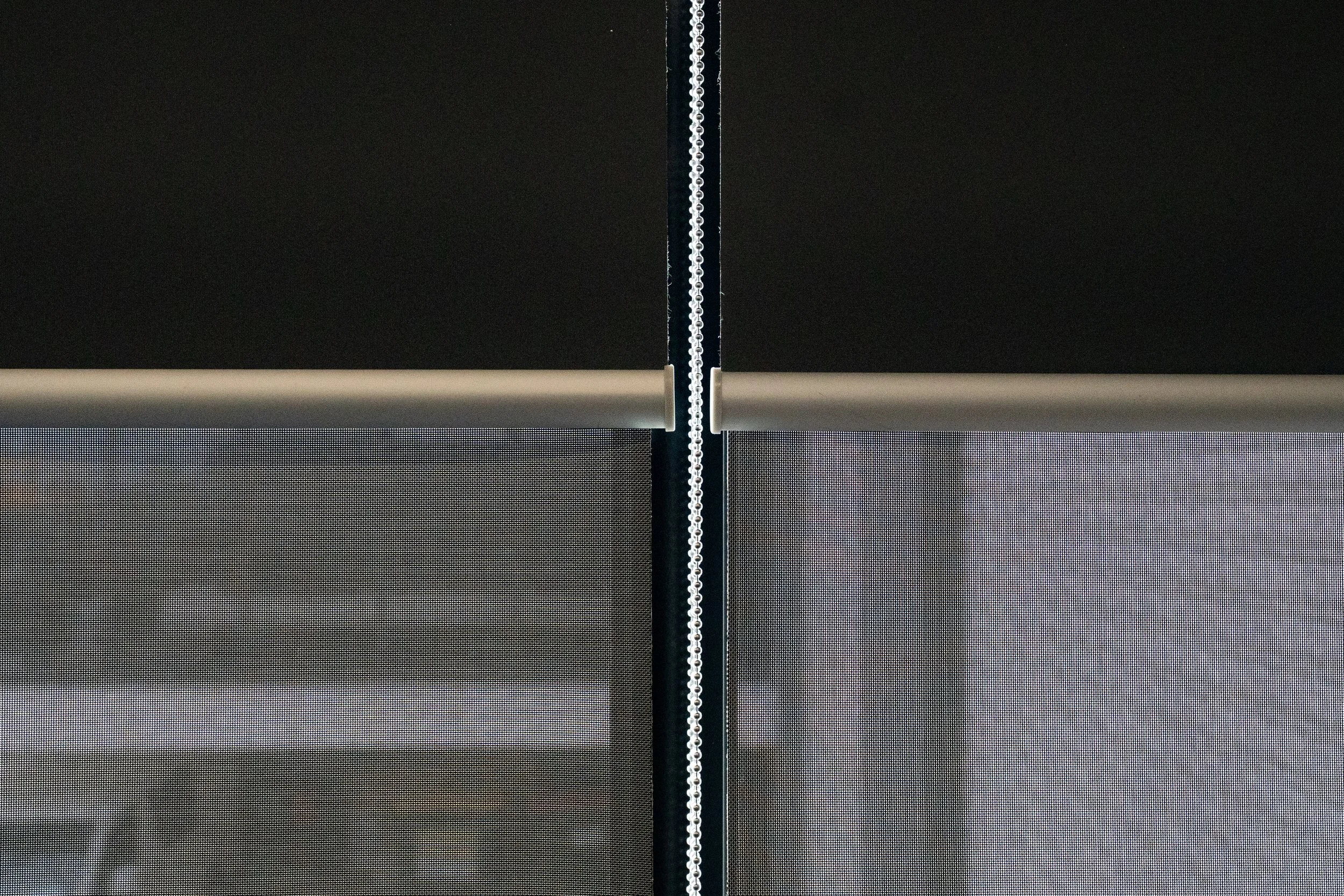 Two double roller blinds meeting: blockout above, sunscreen below