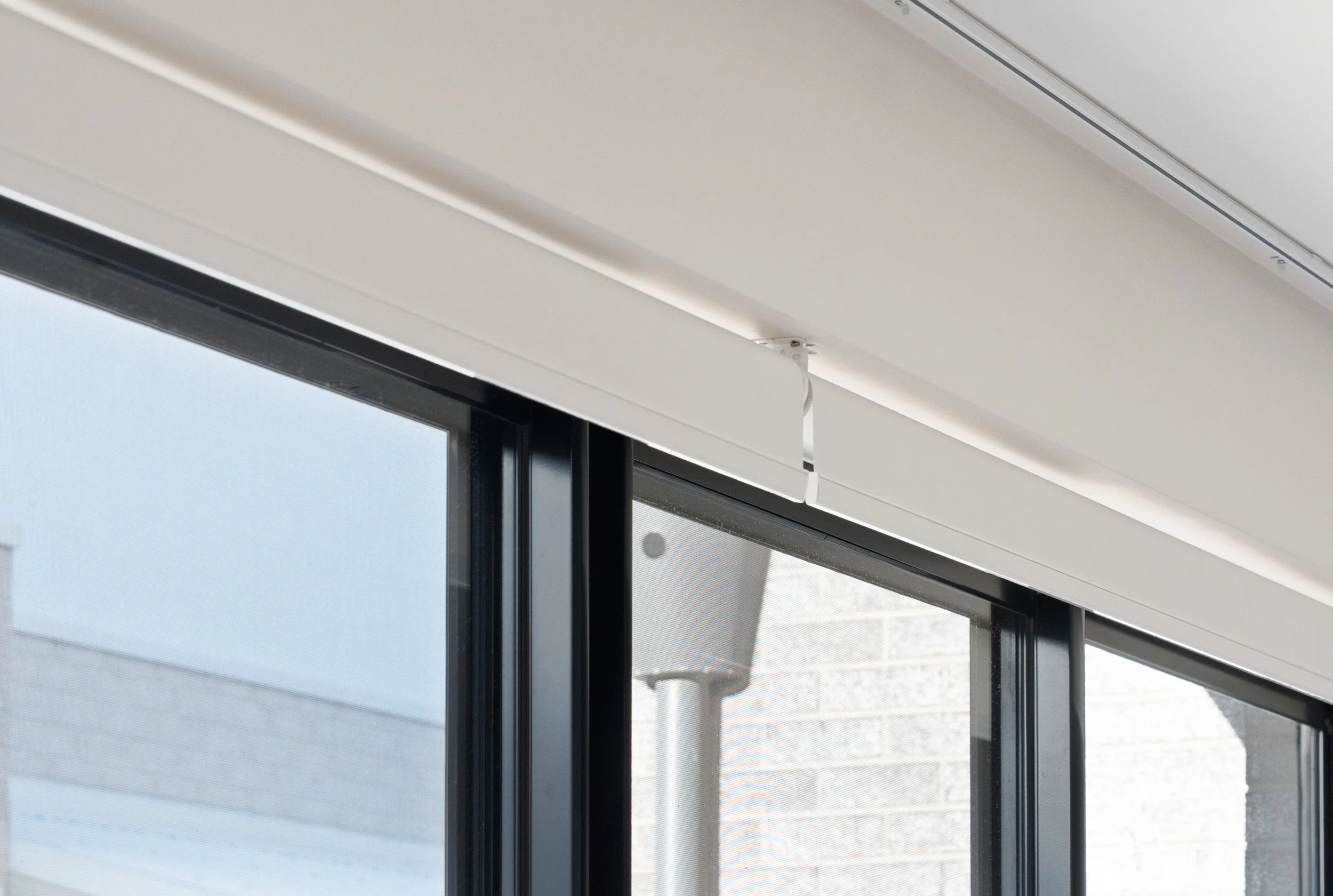 Close-up of two roller blinds at the top of a black-framed window