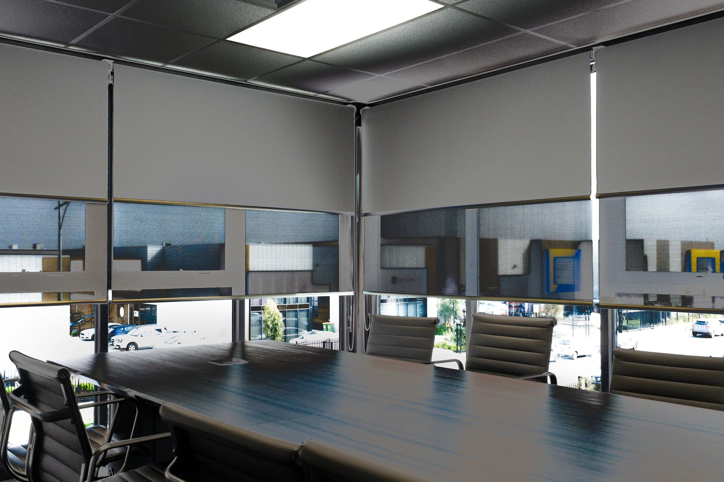 Boardroom table with double roller blinds lowered to different heights