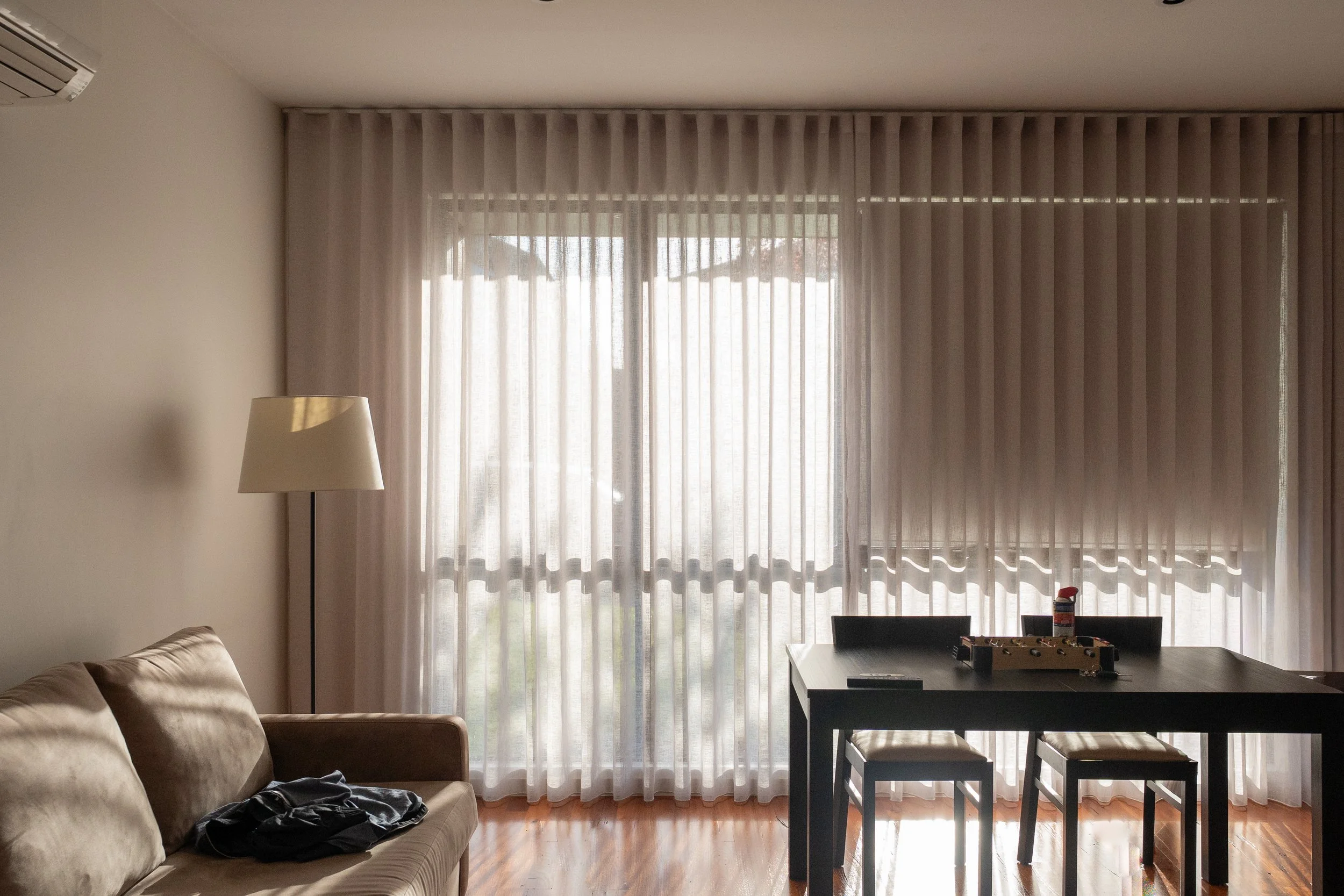 Sheer curtains layered over roller blinds in a living and dining room