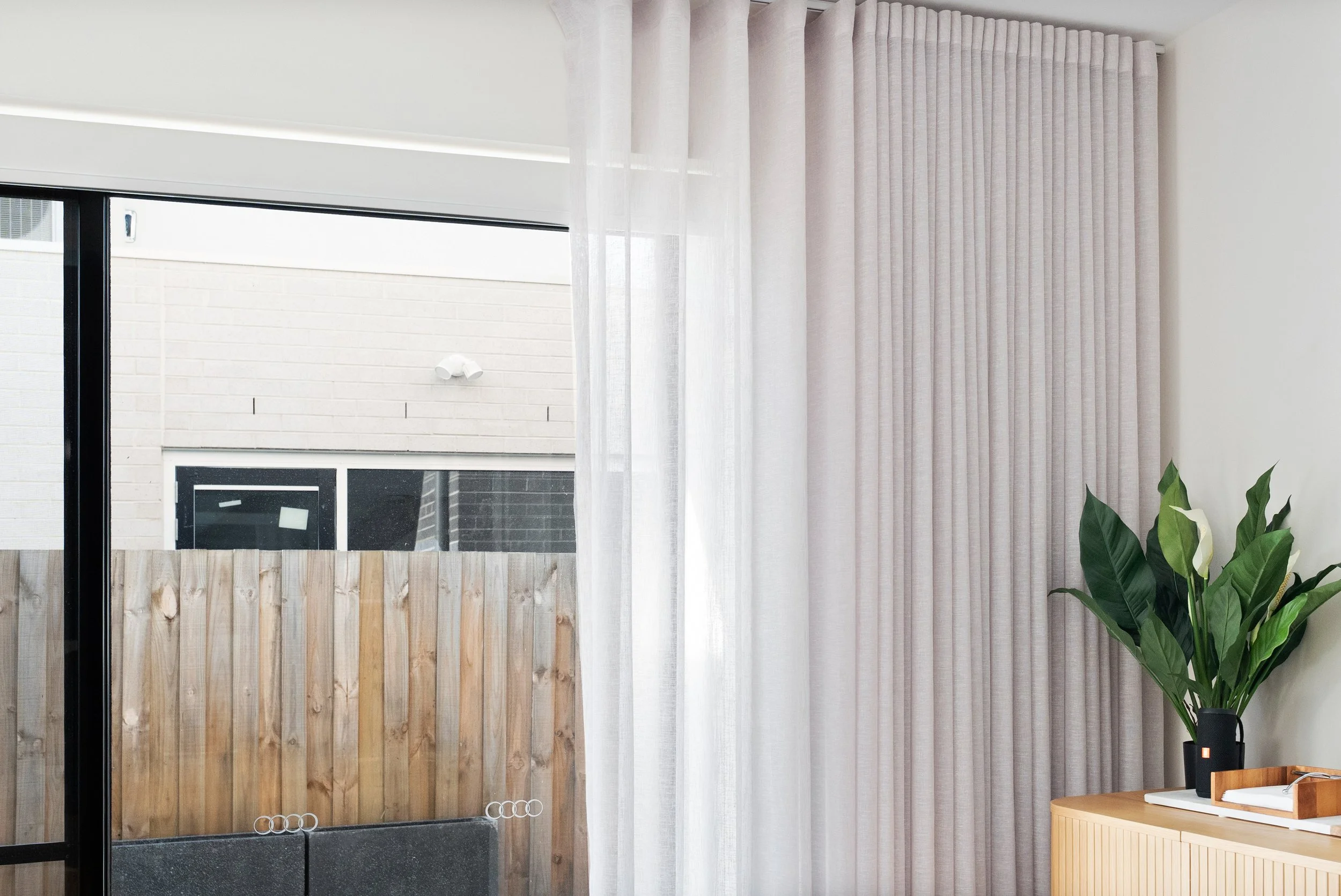 Sheer curtain drawn back beside a black-framed sliding door in a Spotswood home