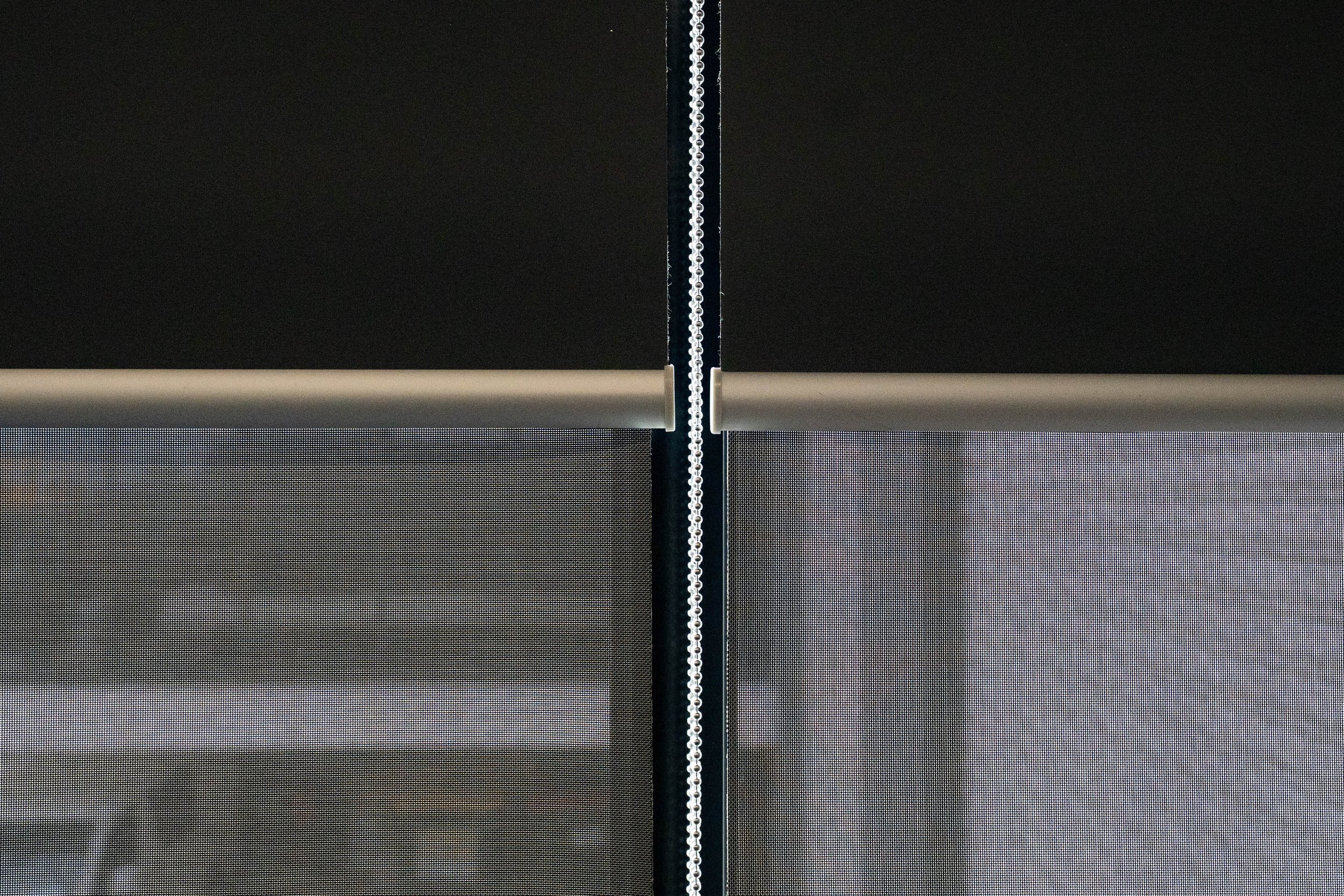 Double roller blinds close-up: blockout layer above, sunscreen layer below