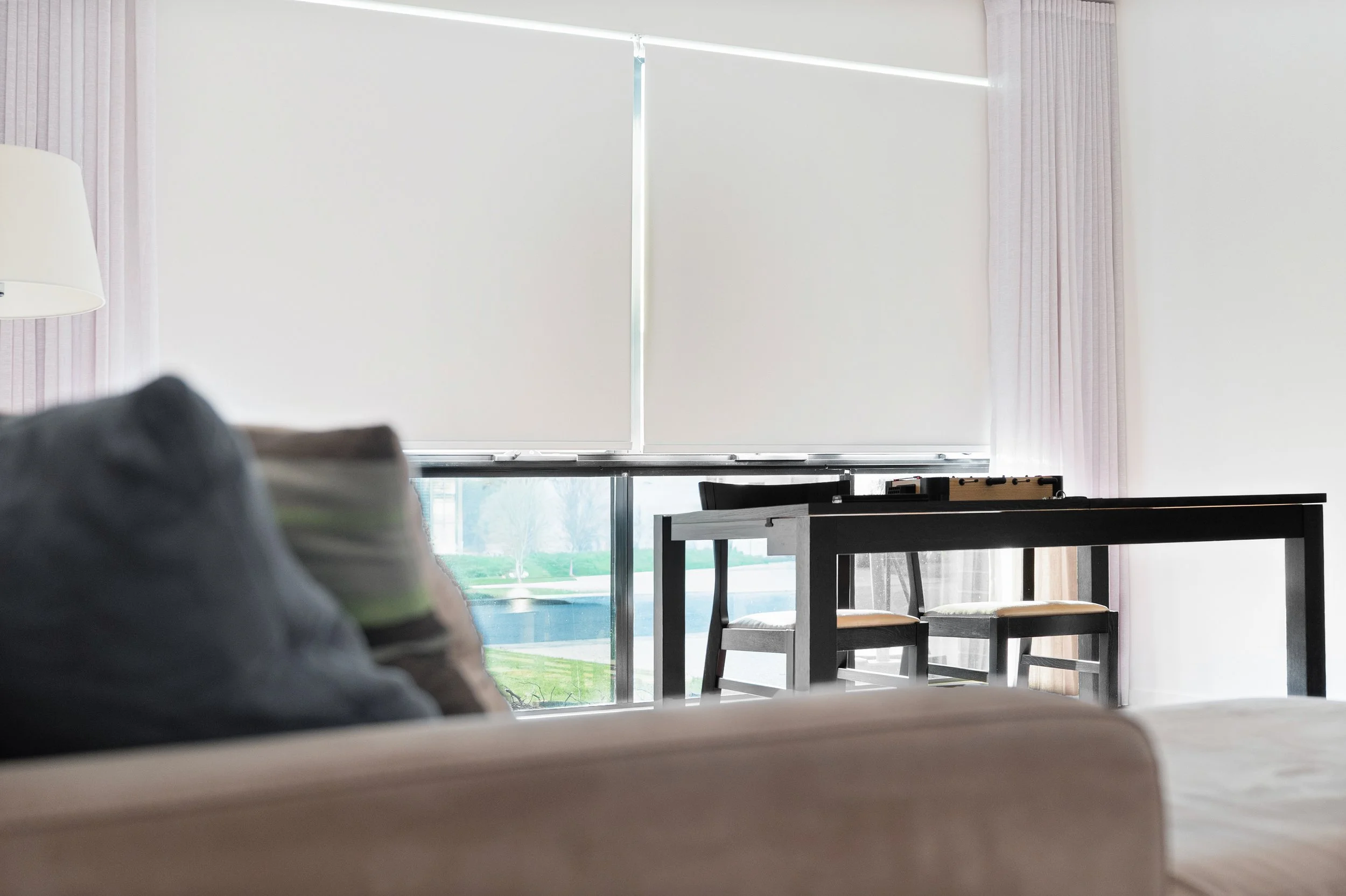 Living room with roller blinds lowered and a sofa in the foreground