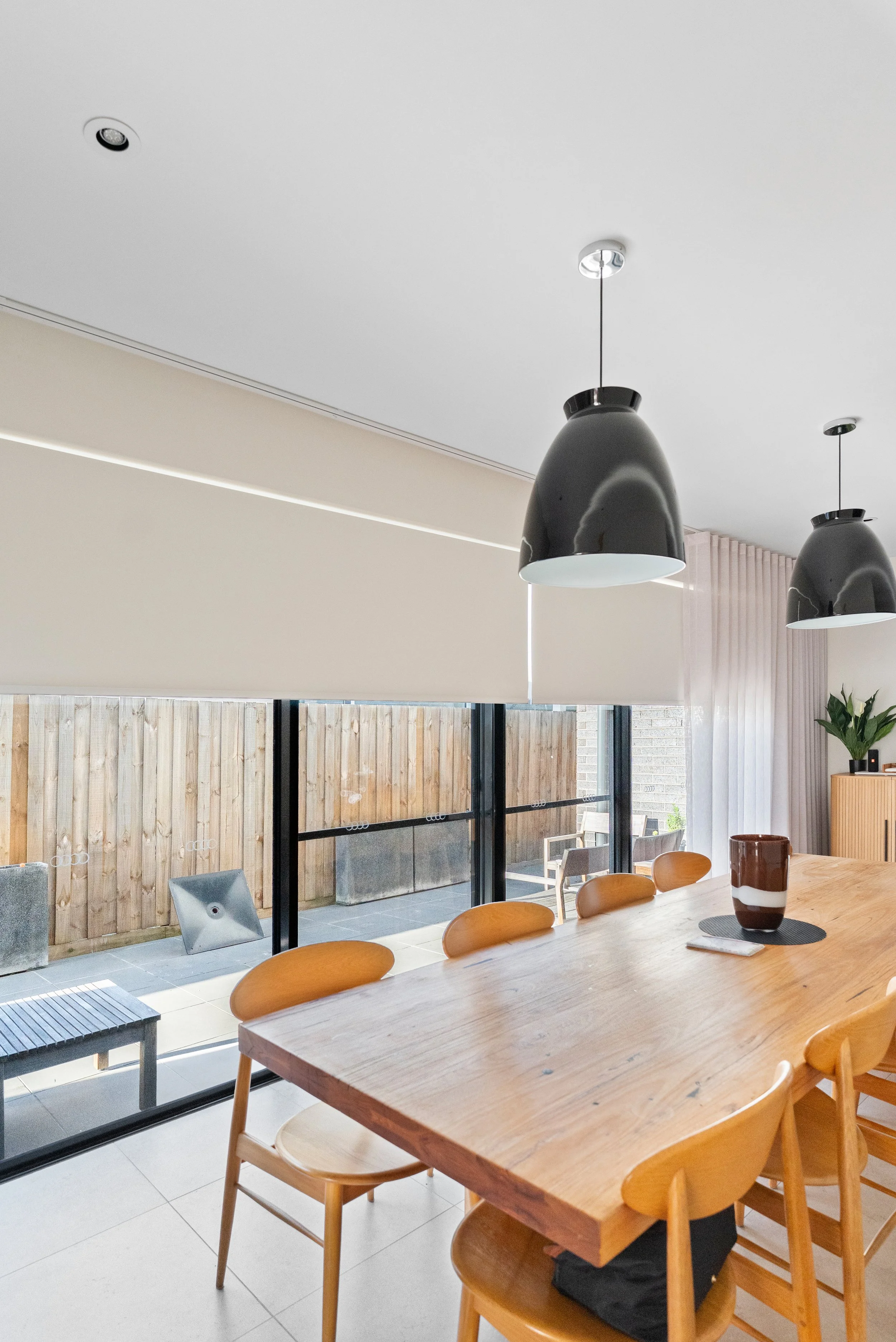 Roller blinds part-lowered above sliding doors in the dining area