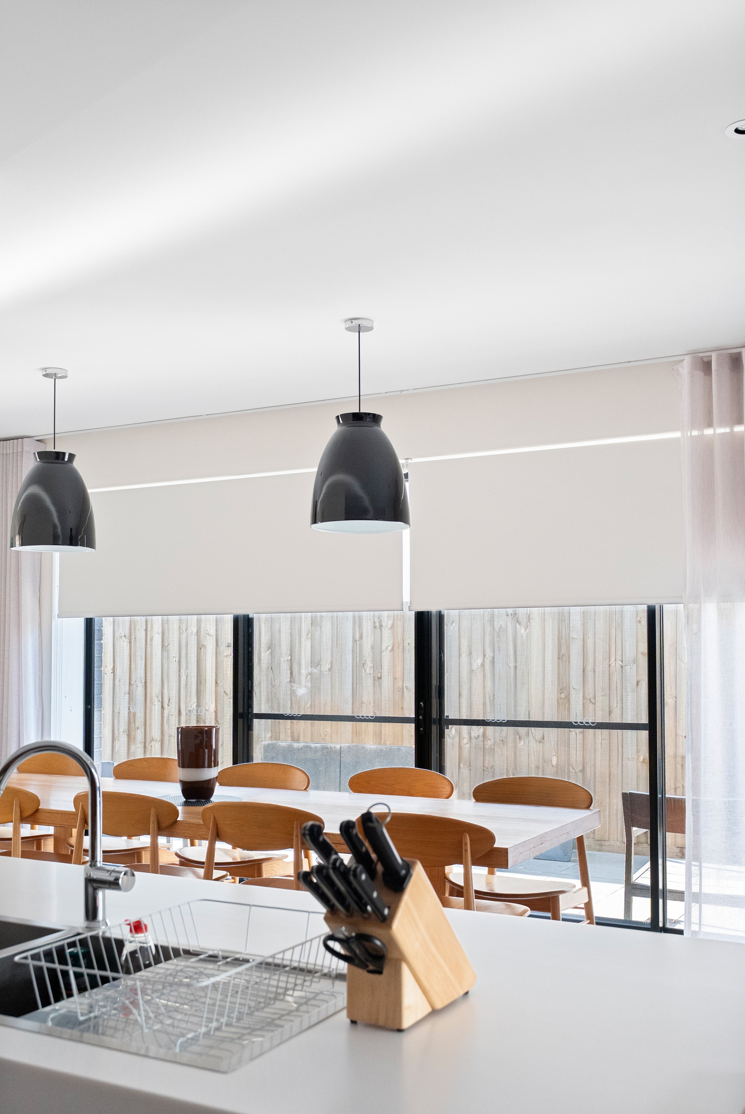 Roller blinds part-lowered across the dining room windows, seen from the kitchen