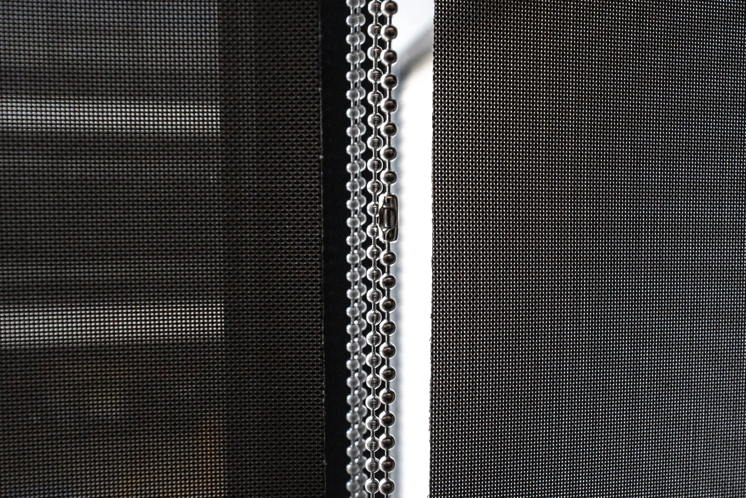 Close-up of sunscreen roller blind fabric with control chains