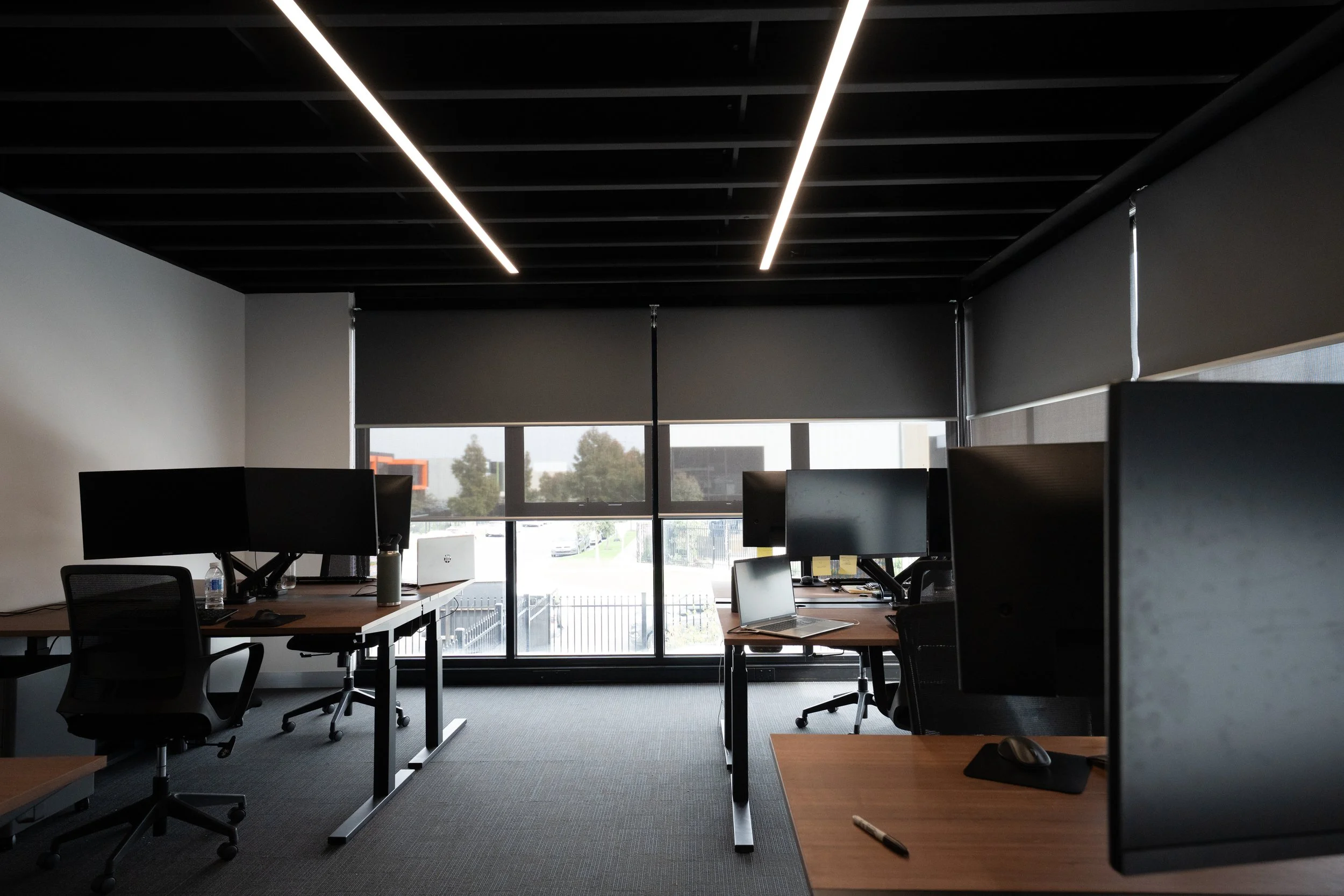 Office workstations beside windows fitted with roller blinds