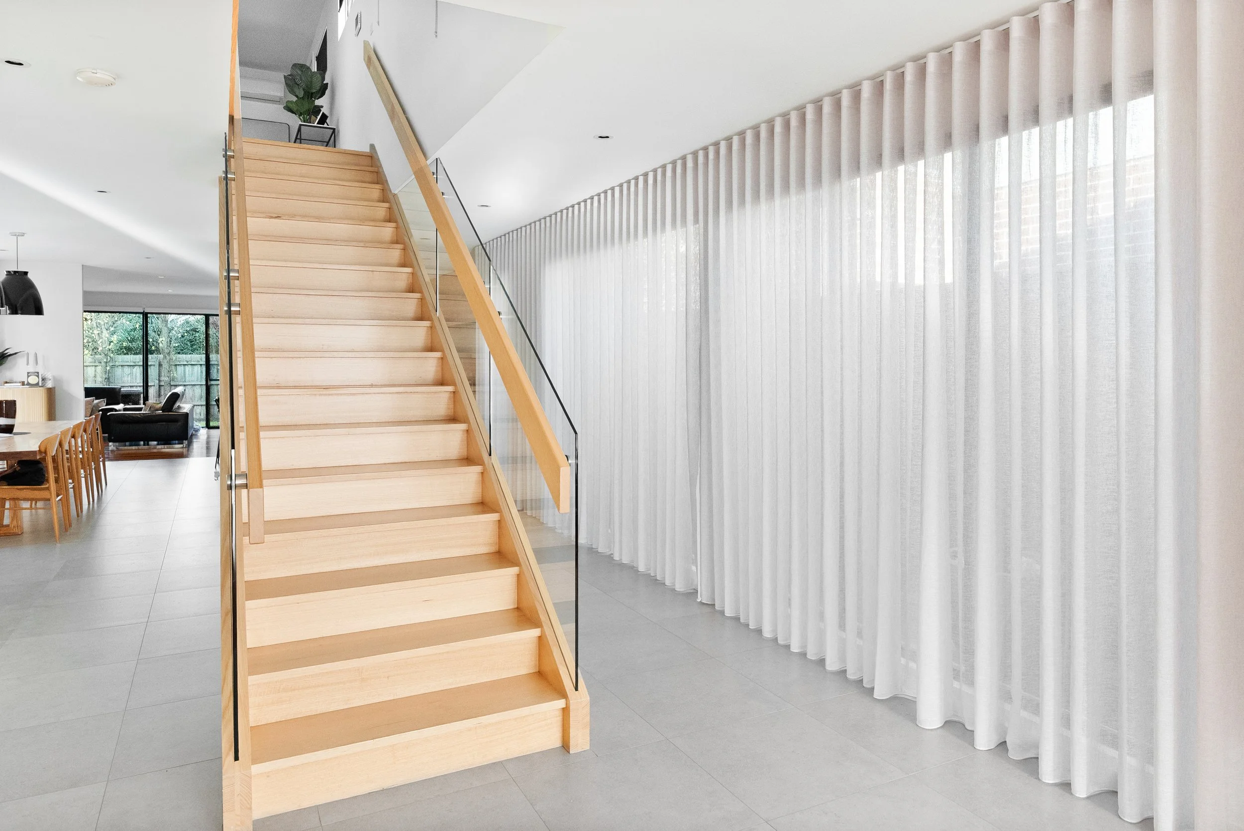 Full-height sheer curtains running along the stairwell and hallway