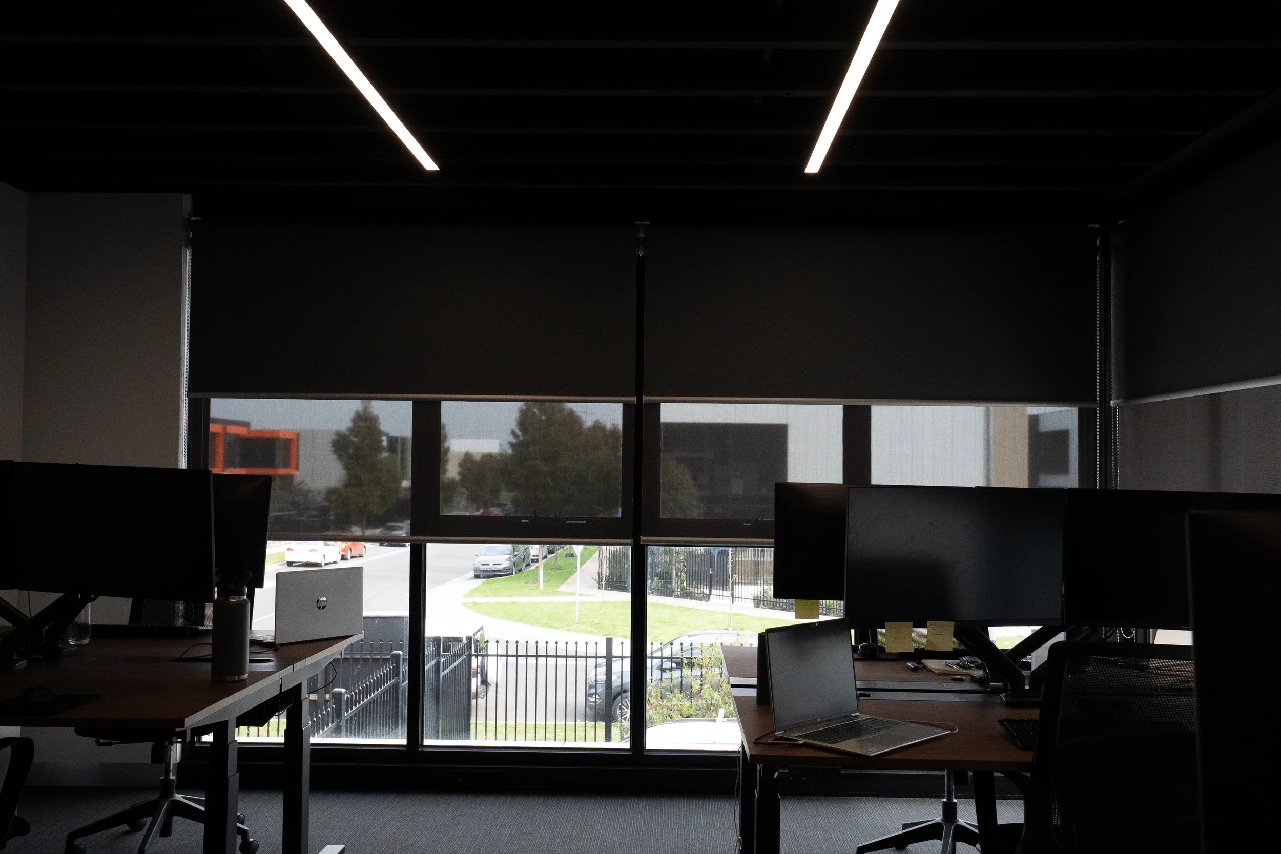 Office desks with sunscreen roller blinds part-lowered on the windows