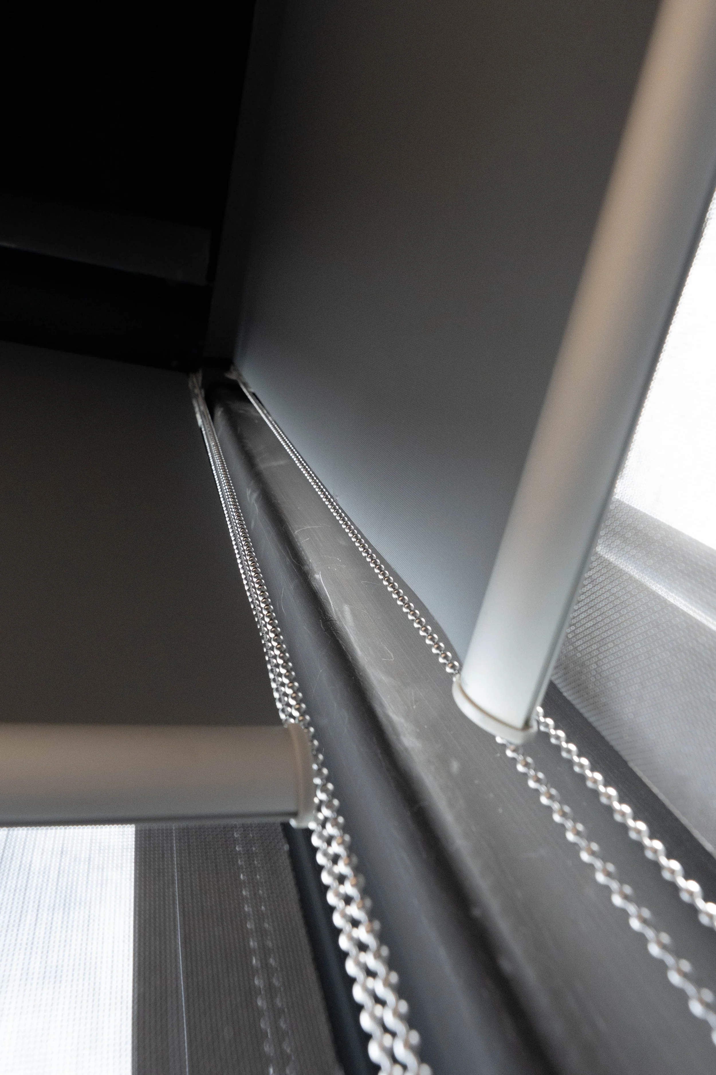 Double roller blind bracket with two tubes and control chains, seen from below