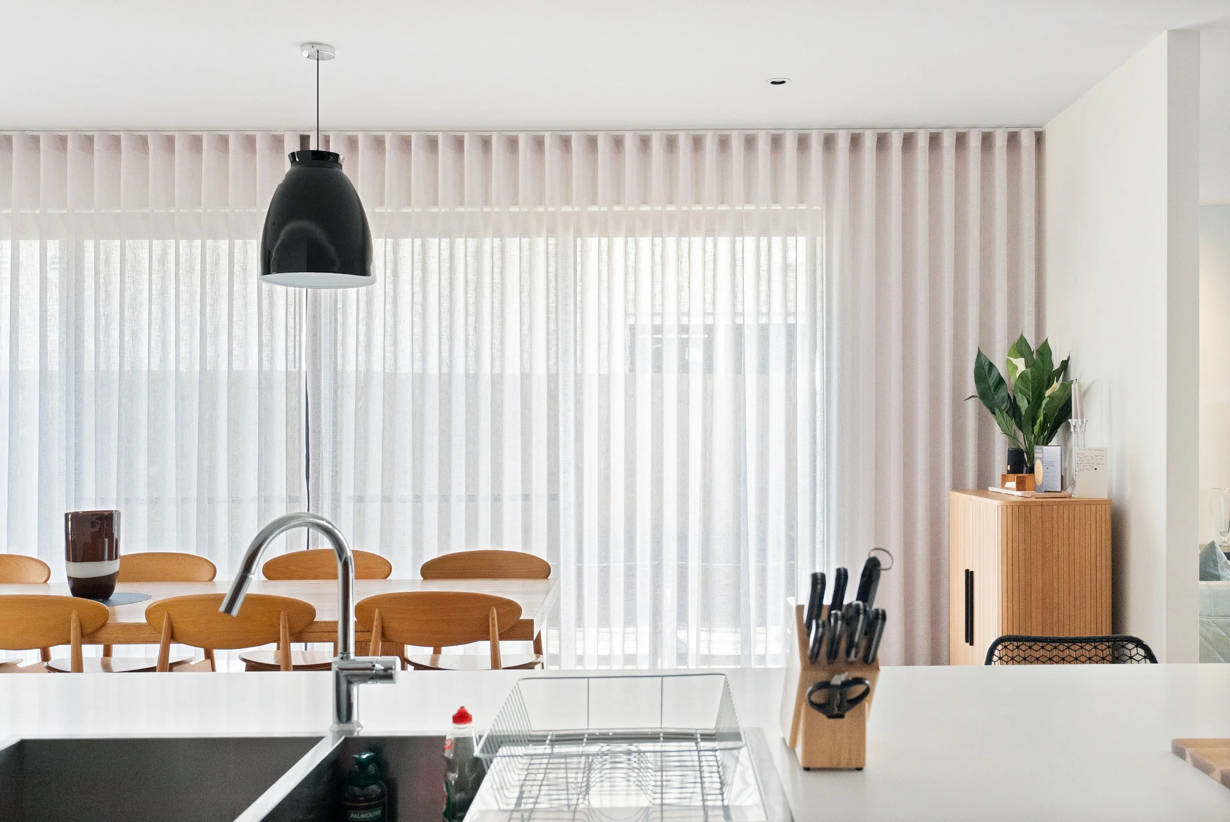 Sheer curtains closed along the dining room wall, seen from the kitchen