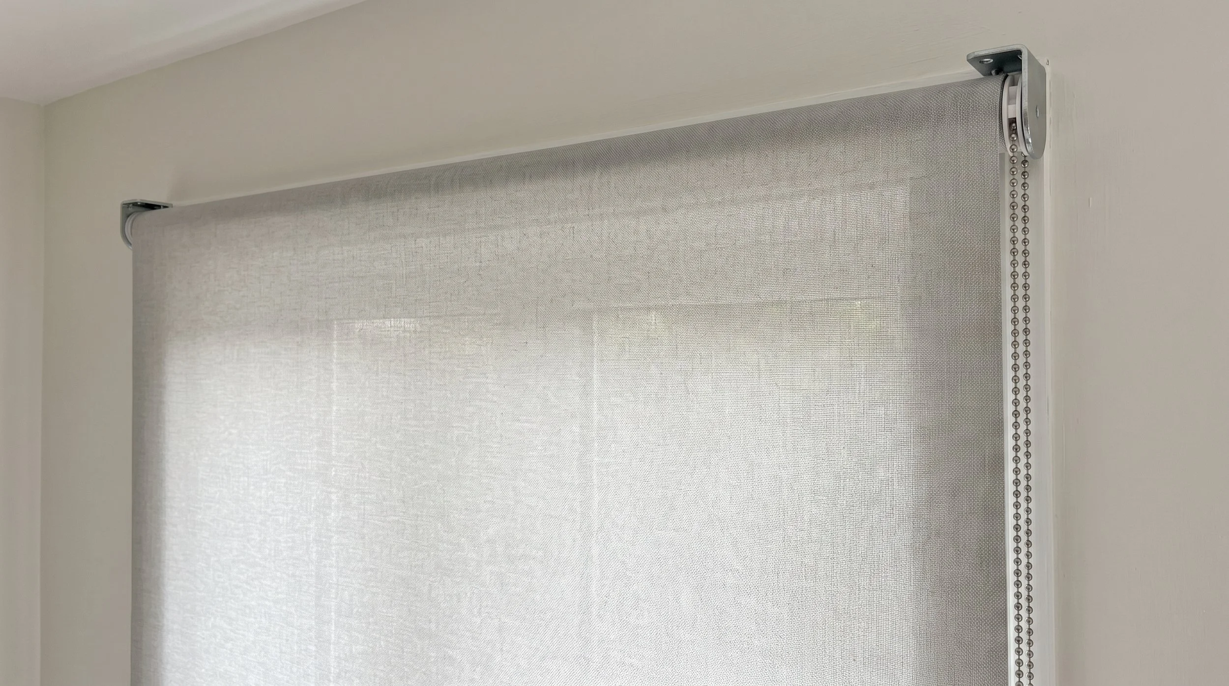 Face-fit sunscreen roller blind mounted above the window frame