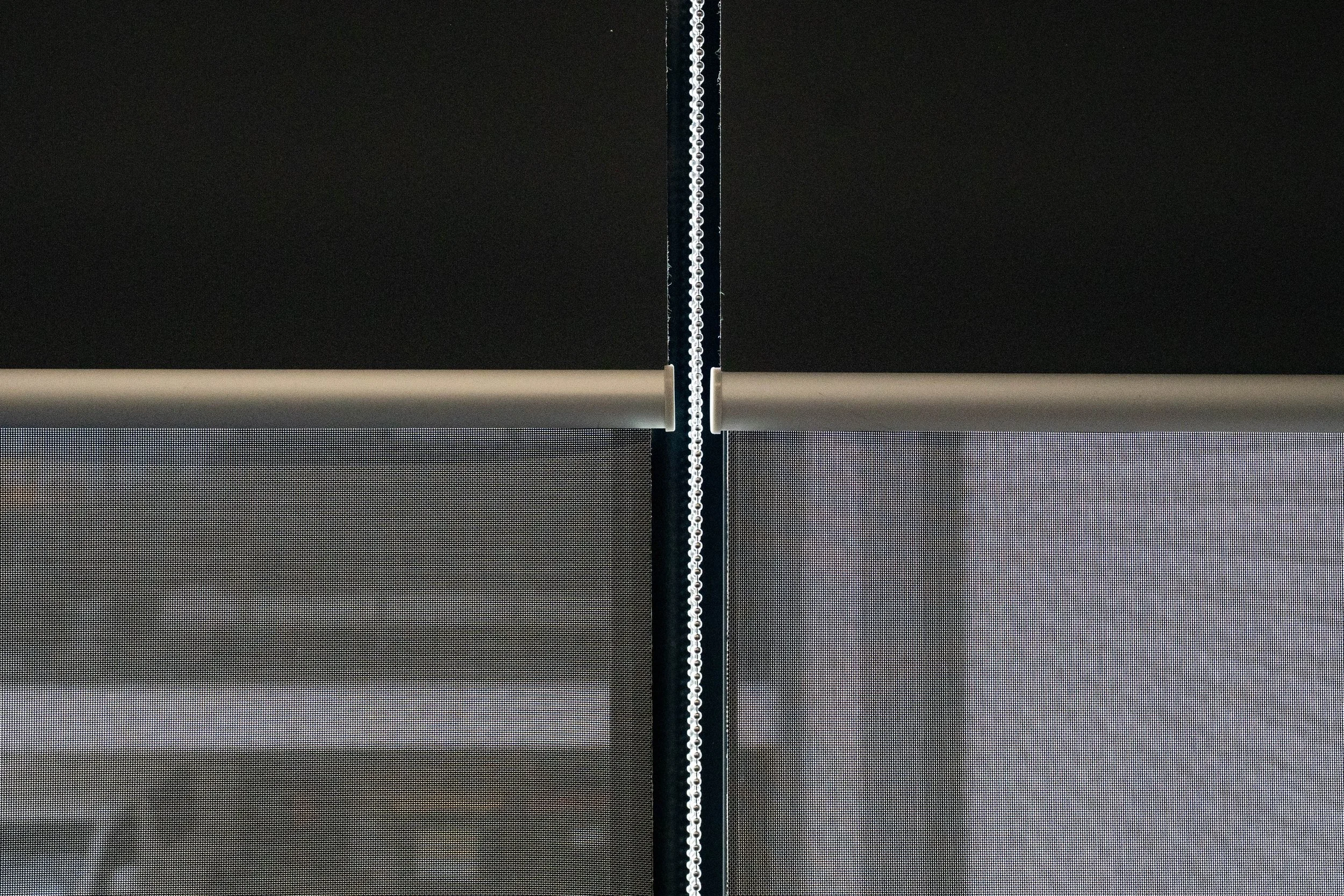 Double roller blinds side by side: blockout layer above, sunscreen layer below