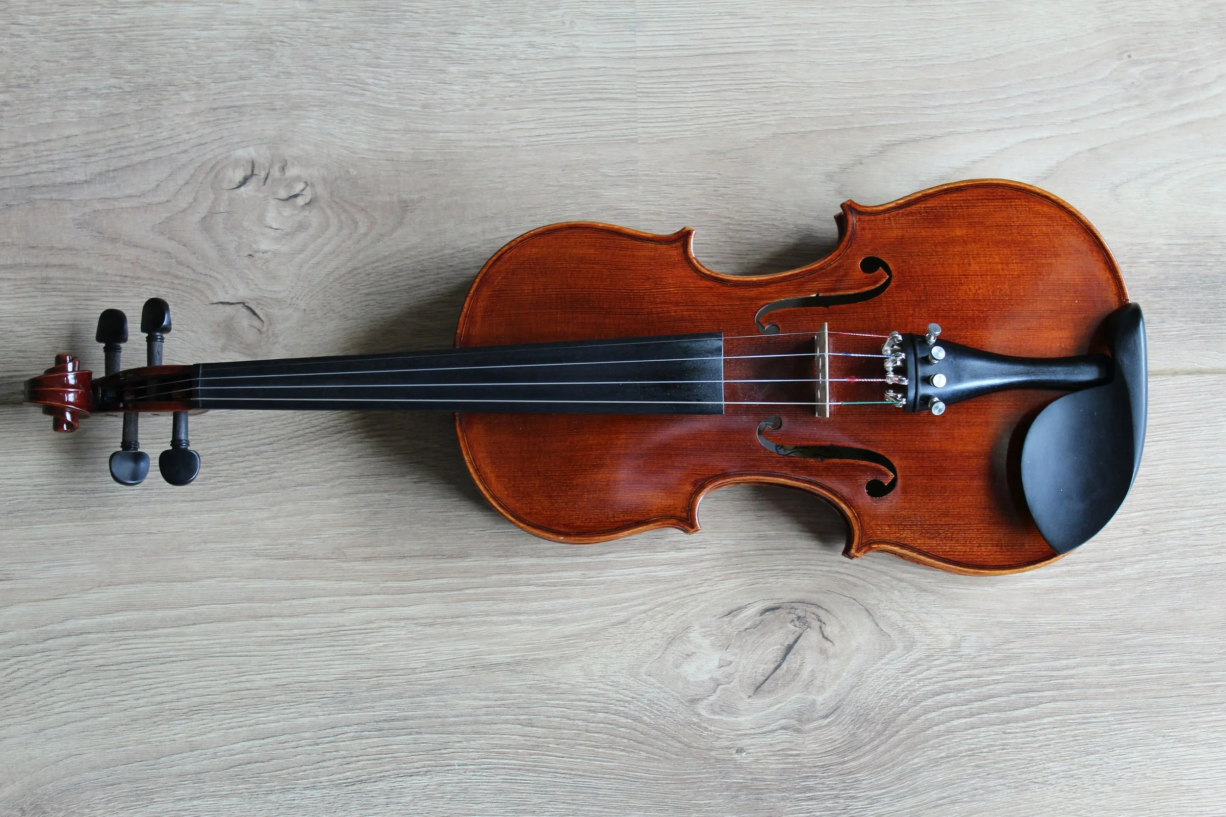 photo of a violin resting on a white wooden tabletop