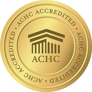 ACHC accreditation emblem with gold background and a building icon in the center.