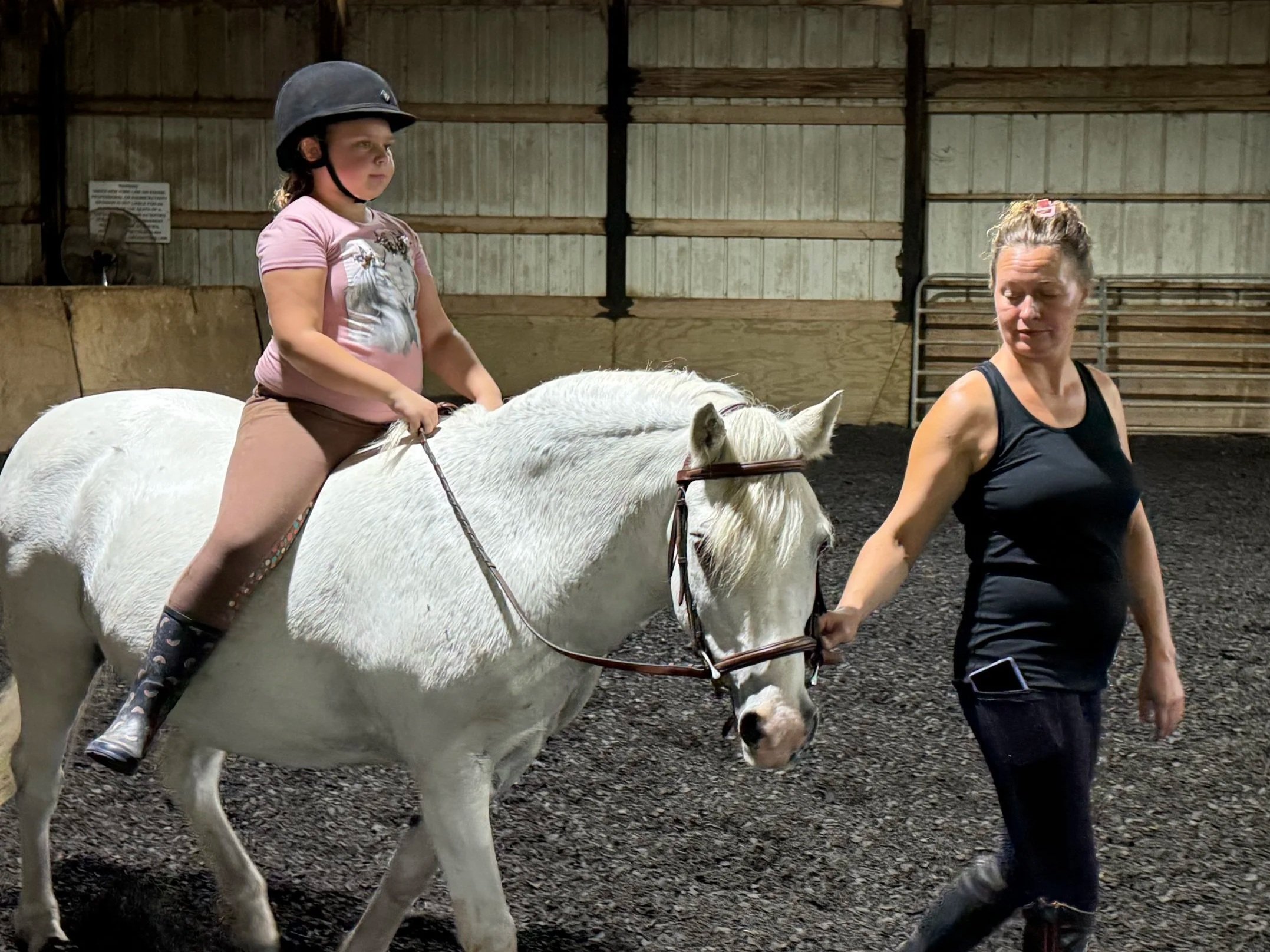 Daun Hohman guiding a young rider during a horseback riding lesson