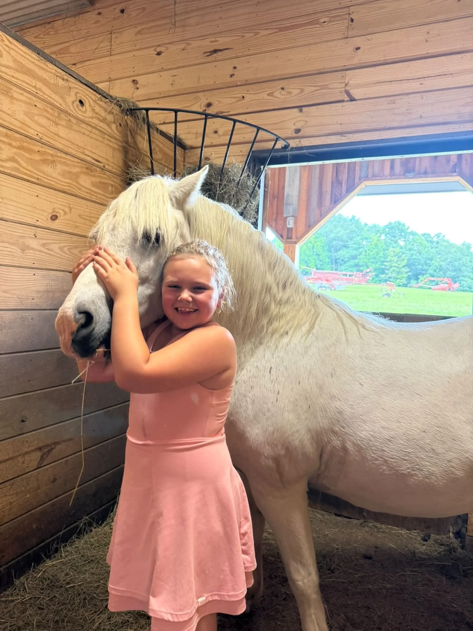 Child hugging a white horse at Shallow Creek Stables