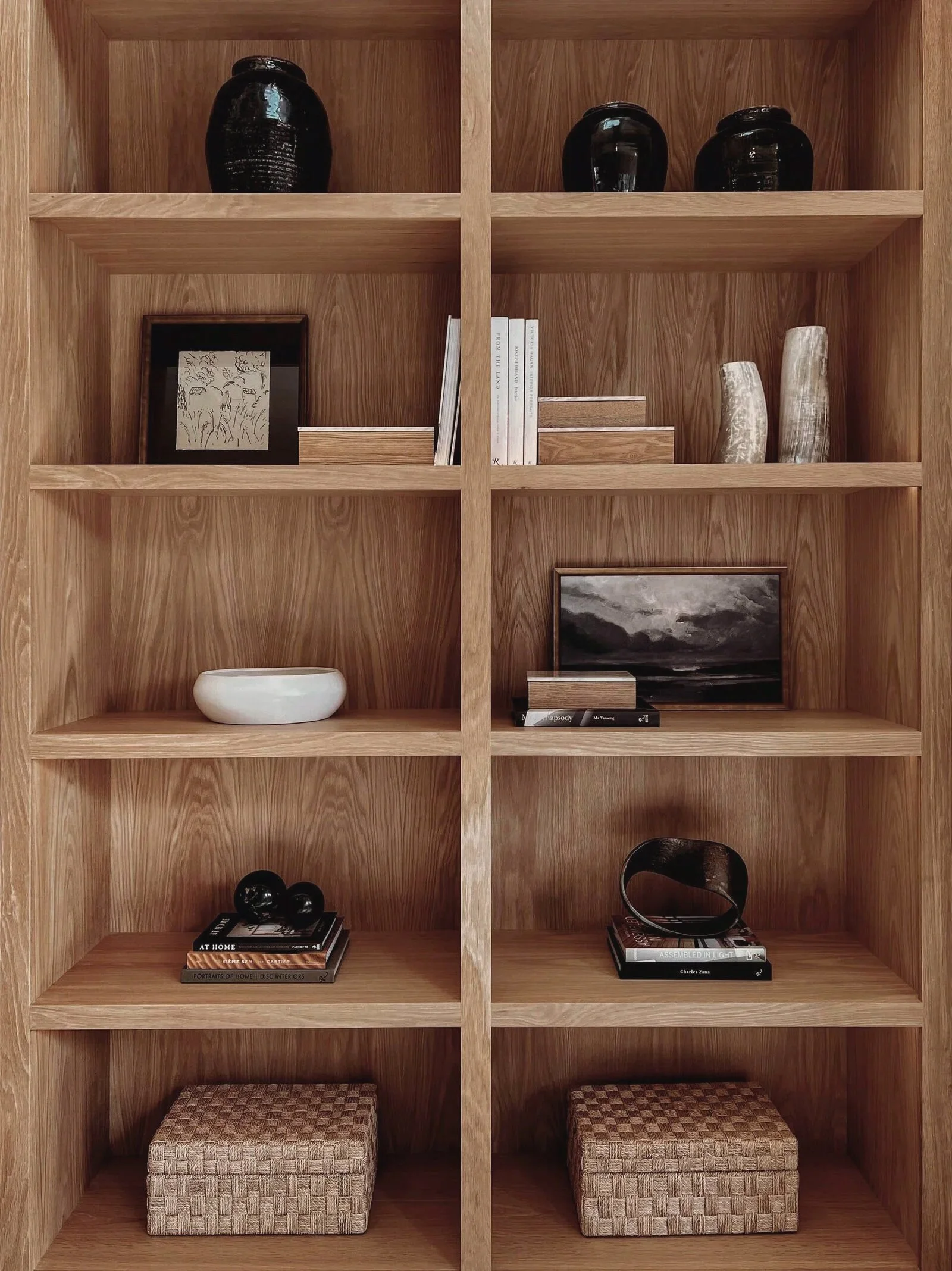 A wooden bookshelf with six compartments, each containing decorative items, books, or storage boxes, with some items arranged on the shelves.