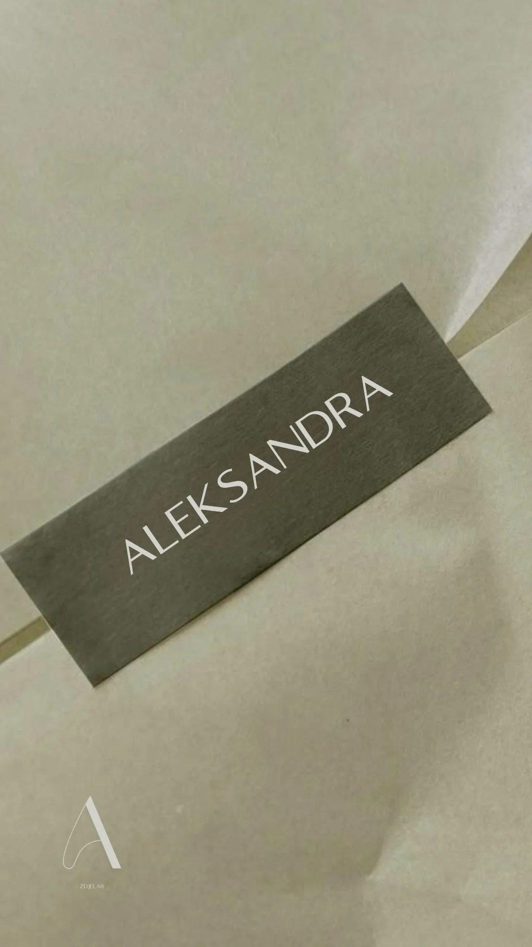 Close-up of a nameplate on a light-colored wall that reads 'ALEXANDRA' in uppercase letters.