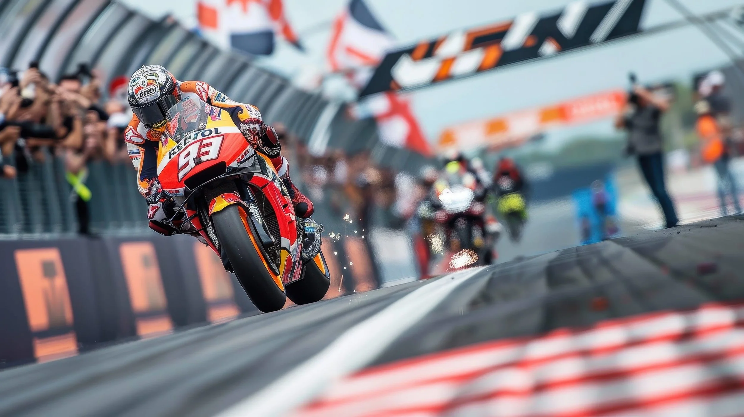 A motorcycle racer in full gear rides on a race track. The rider is kicking up sparks as they lean into a turn, with a crowd and race officials visible in the background.