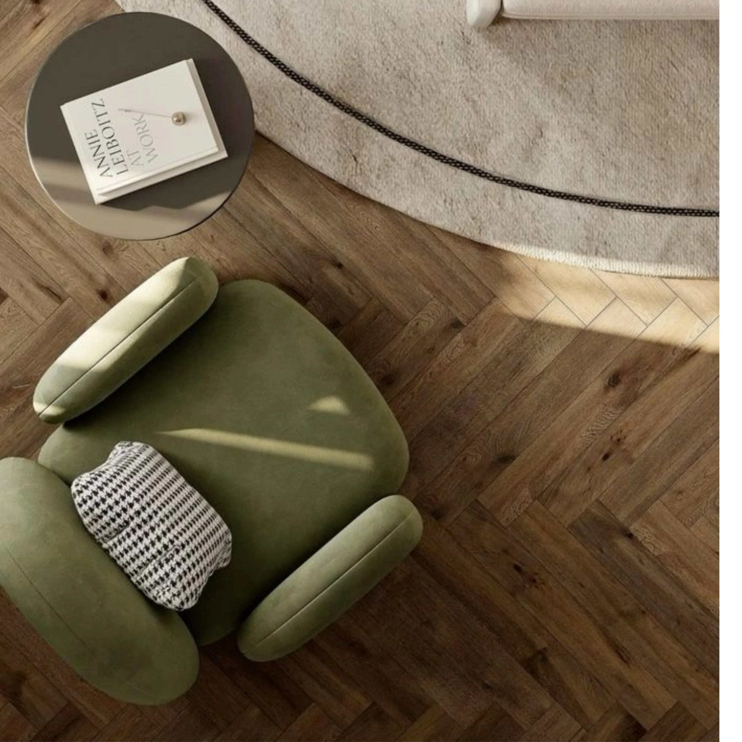 A green armchair with a black and white checkered throw pillow, a beige carpet with black trim, a dark wood floor, and part of a white piece of furniture.