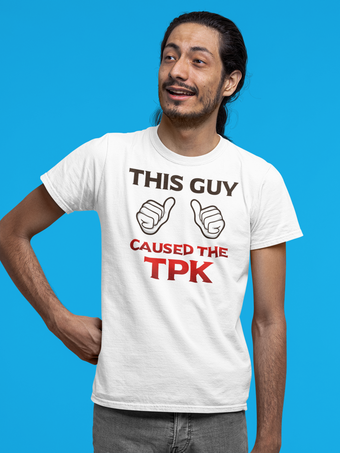 Man wearing a white t-shirt with bold text and thumbs up graphics, standing against a bright blue background. He has long dark hair, a beard, and is smiling.