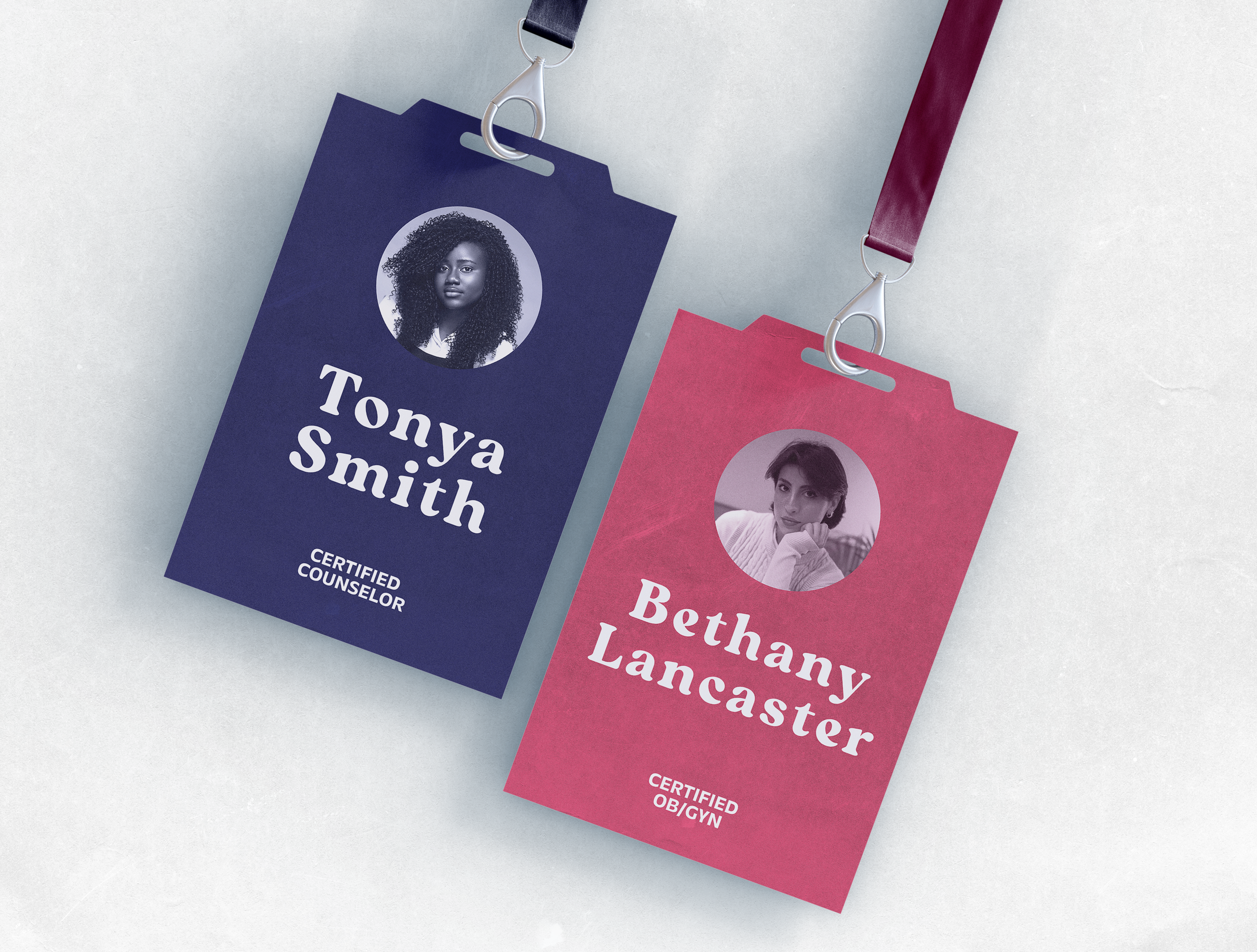 Two professional identification badges, one blue and one pink, labeled "Certified Counselor" and "Certified OB/GYN", with photos of women attached, hanging on a light-colored background.
