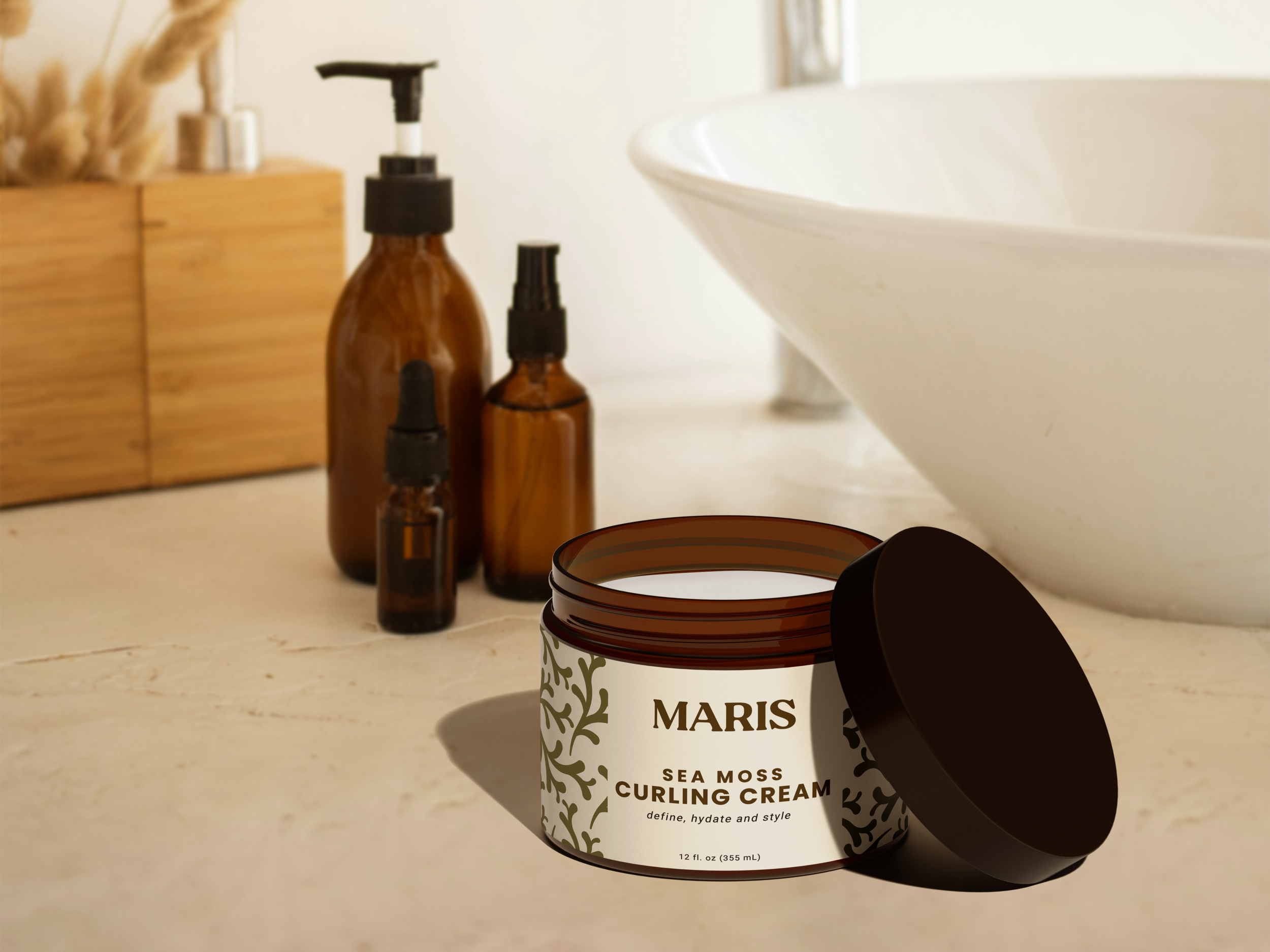 A container of Sea Moss Curling Cream labeled 'Maris' with an open black lid in front of brown bottles and a wooden box with dried plants beside a white sink.