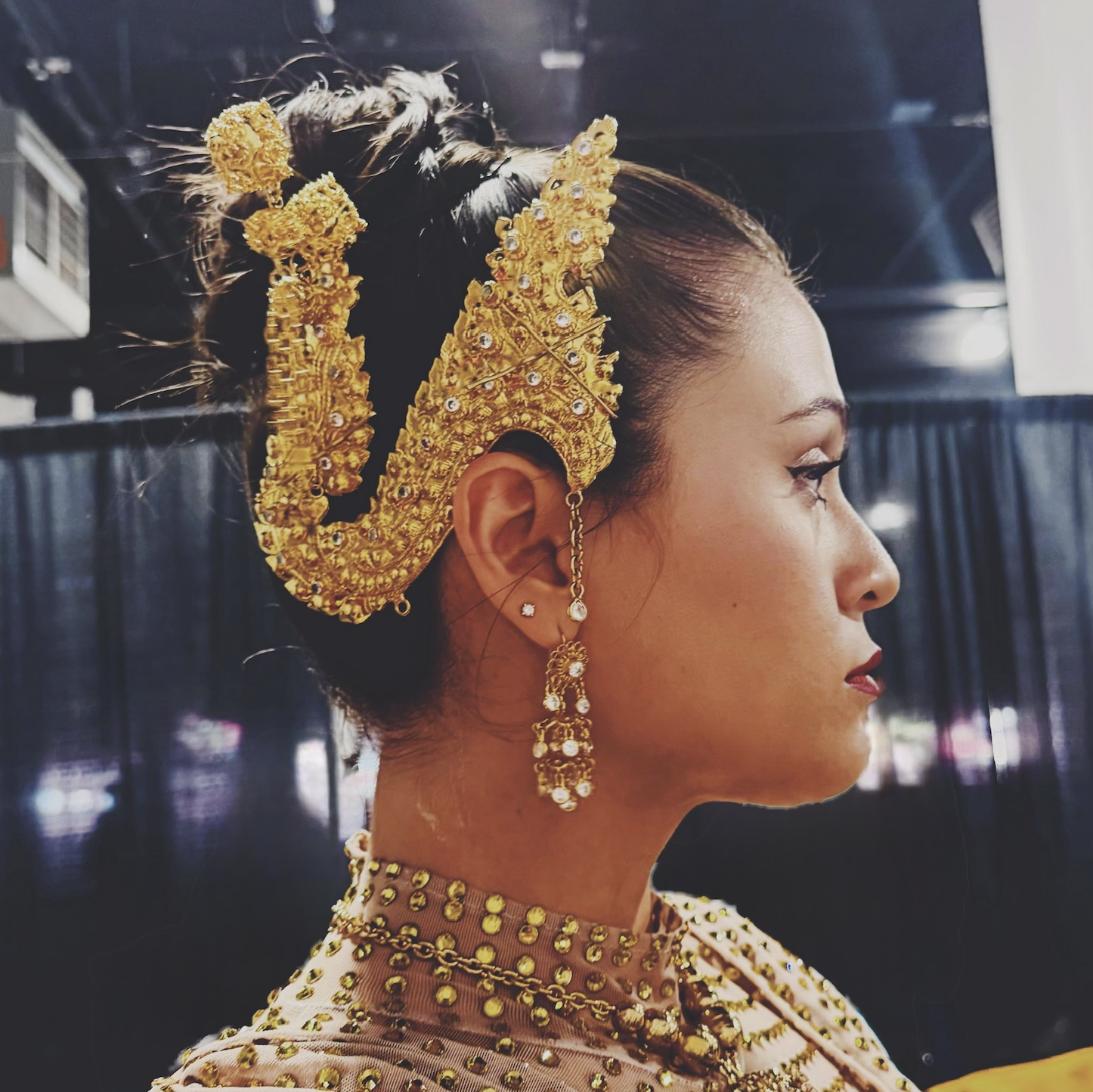 Sara Gregor (The Apsara Creative) wearing traditional gold jewelry and a gold-embellished outfit, with dark hair styled in an updo, by SNOB house for a fashion show in Minnesota