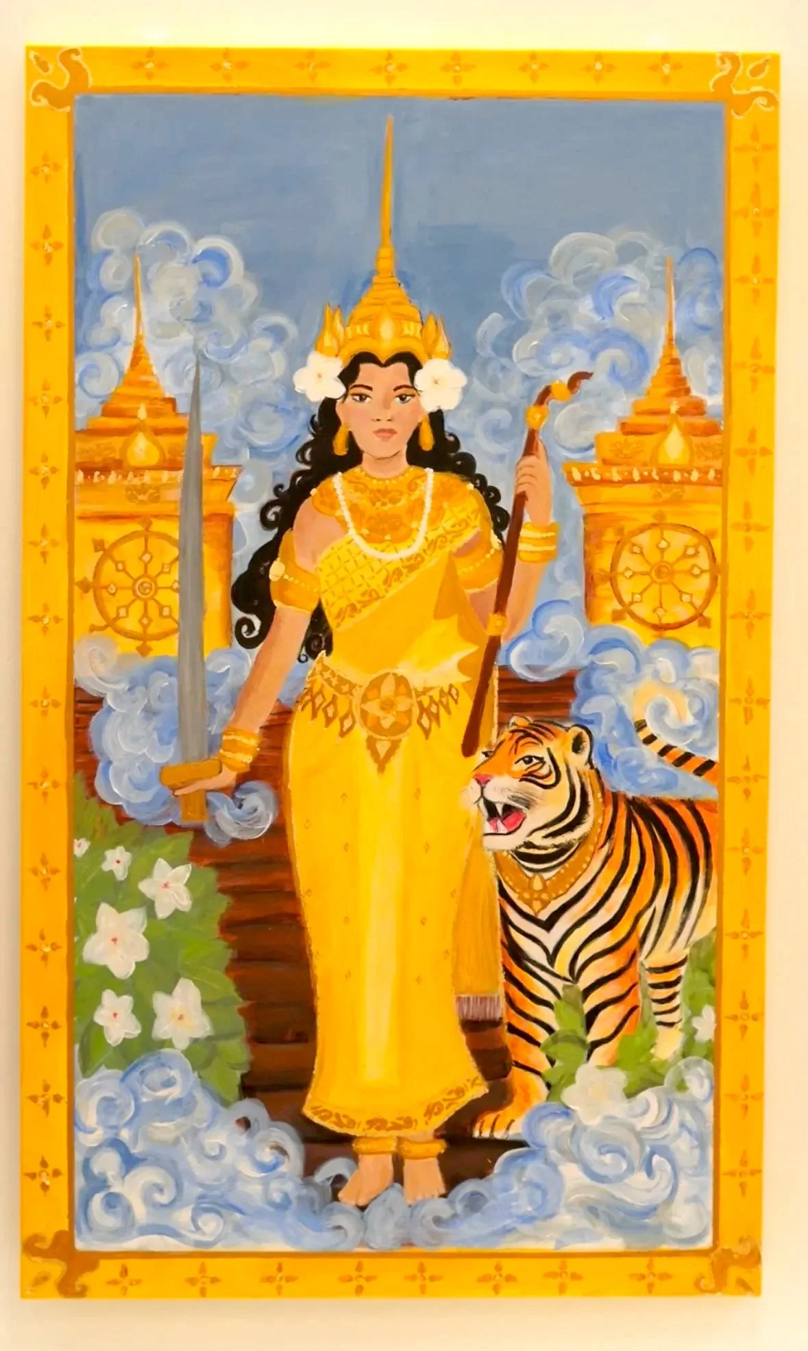 A painted portrait of a mythological figure holding a sword and a flaming torch, wearing a crown and adorned in gold clothing, with a tiger at her feet. The background features clouds and two ornate towers with spires, all framed with a yellow decorative border.