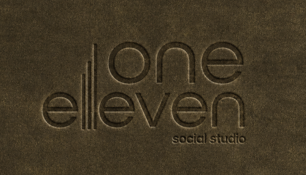 Embossed logo reading "one eleven social studio" on a dark textured surface.