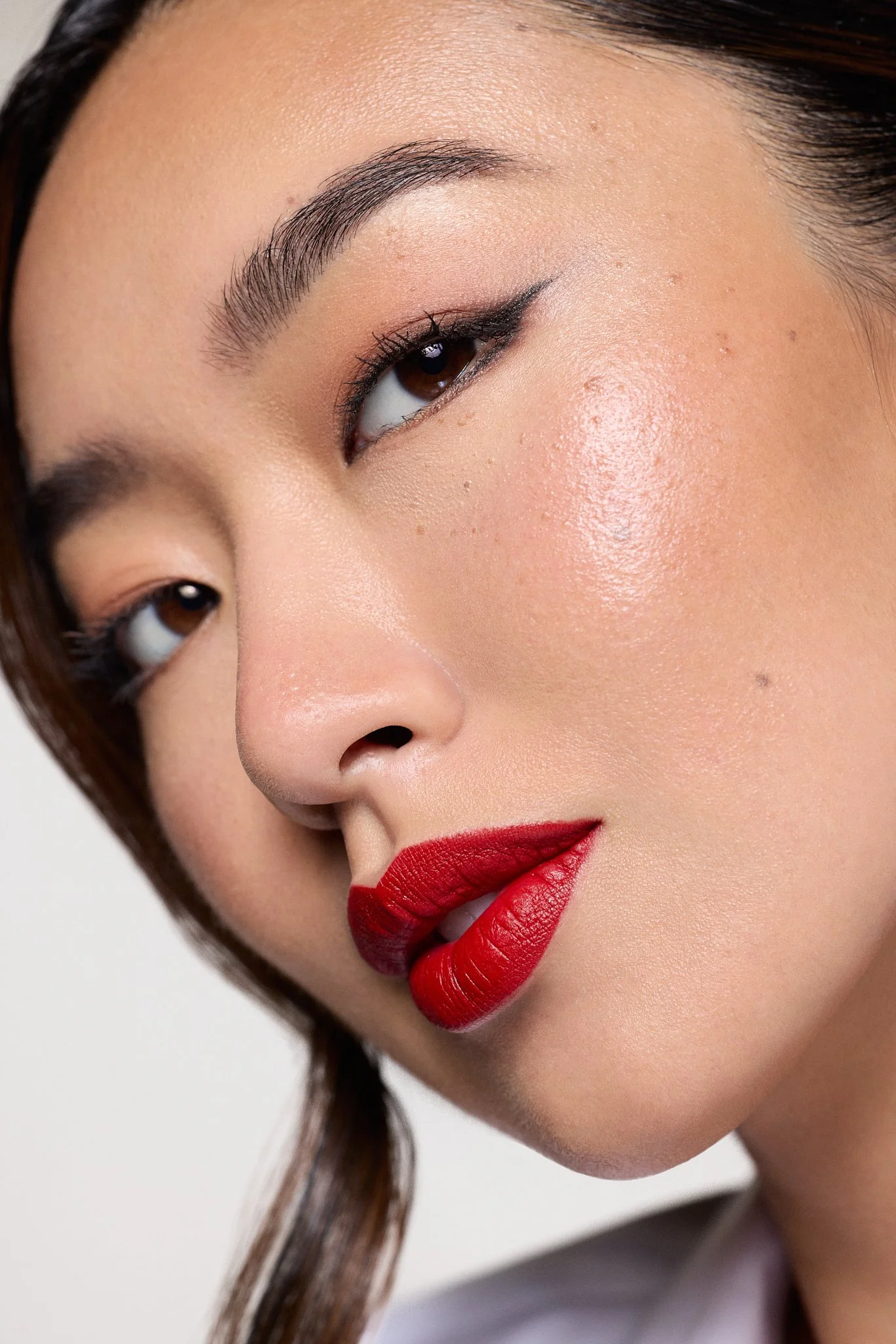 Close-up of a woman's face showing her eye with makeup, red lipstick, and smooth skin.